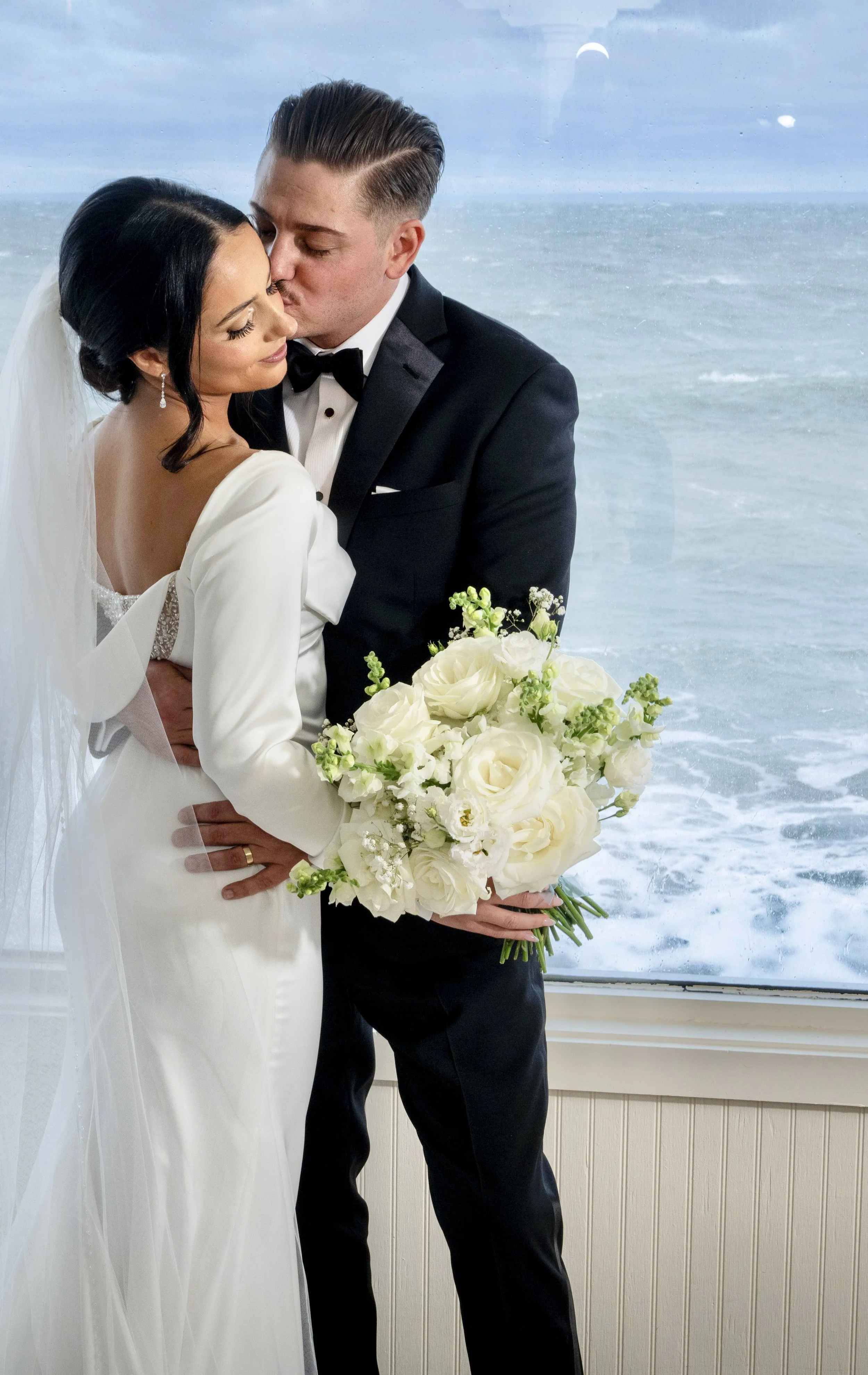 Waterfront wedding couple with all-white peony and rose bouquet