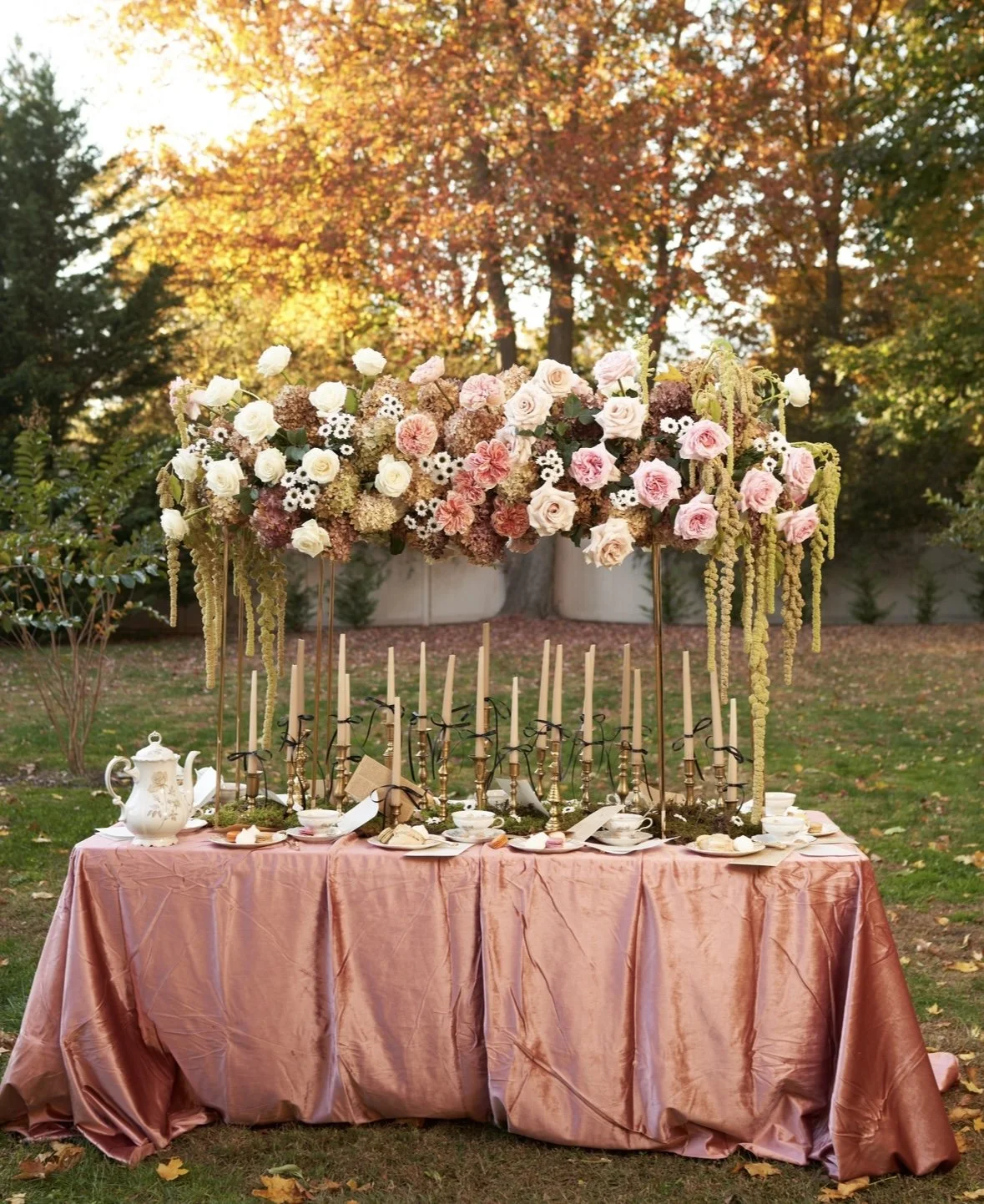 Romantic outdoor tablescape with blush and white flowers floating on gold stands