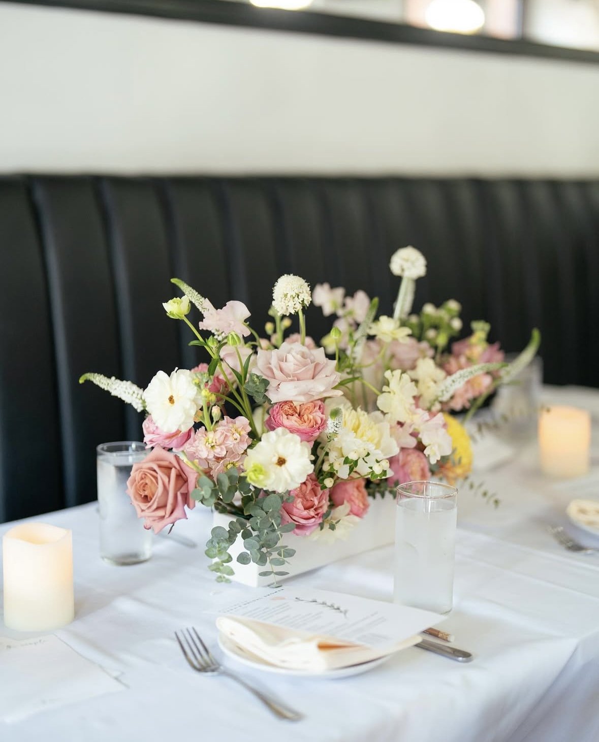 Pink and coral low centerpiece arrangement with candles on white table