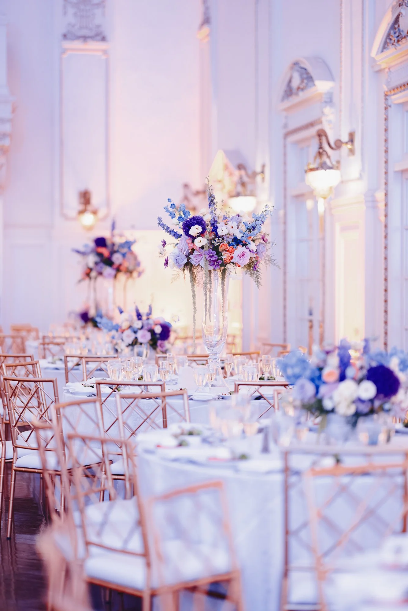Dramatic tall purple and pink centerpieces in elegant wedding ballroom.