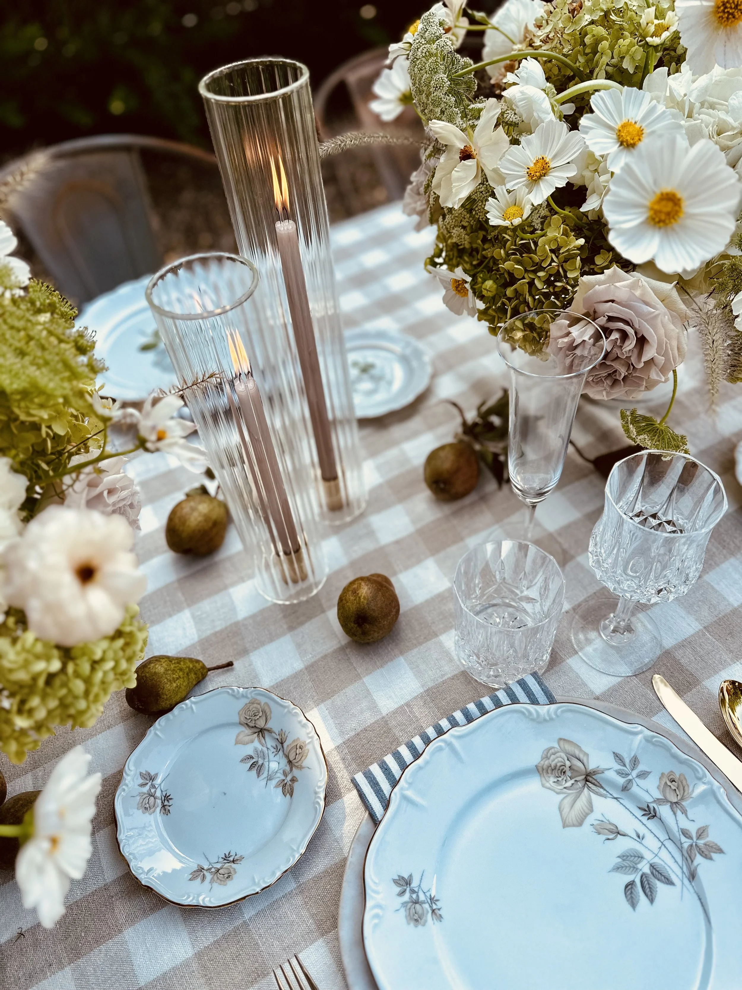 Elegant wedding tablescape with vintage blue floral plates, white cosmos arrangements, tall candle vases, and gingham runner by Nicole Link Designs.