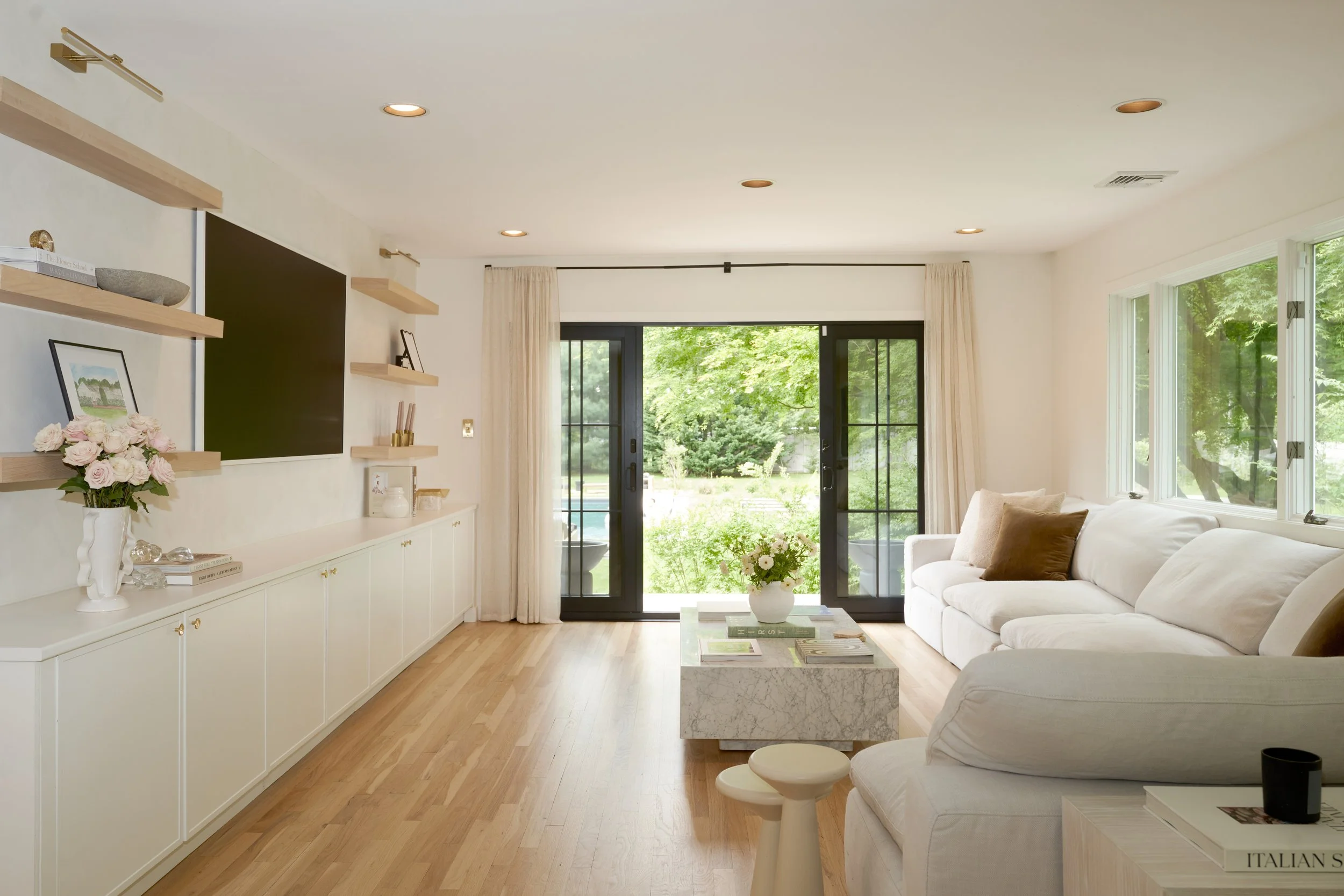 Modern lounge, open concept living room with white sofa, black French doors, and natural oak flooring