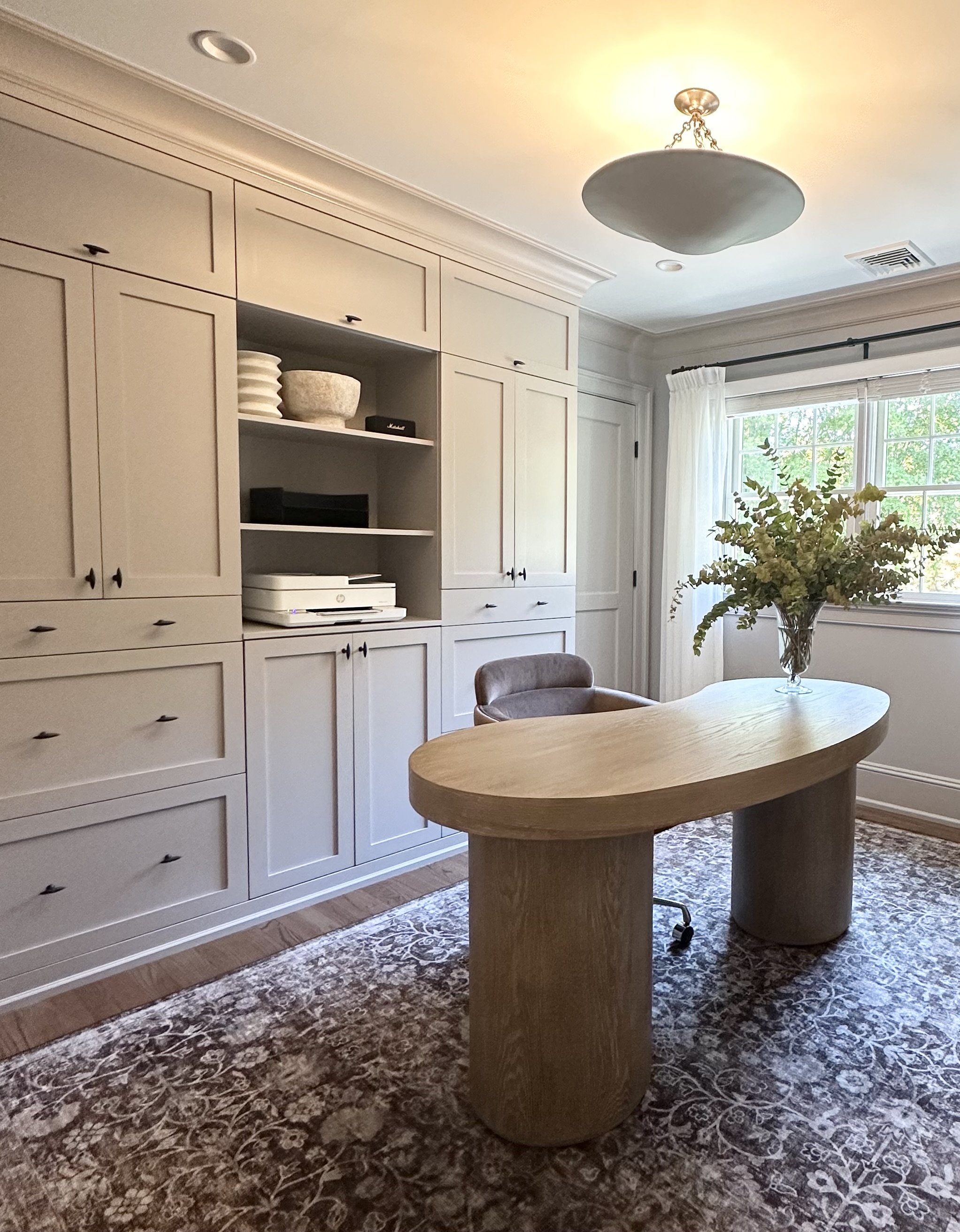 Custom white cabinetry with round oak desk by Nicole Link Designs