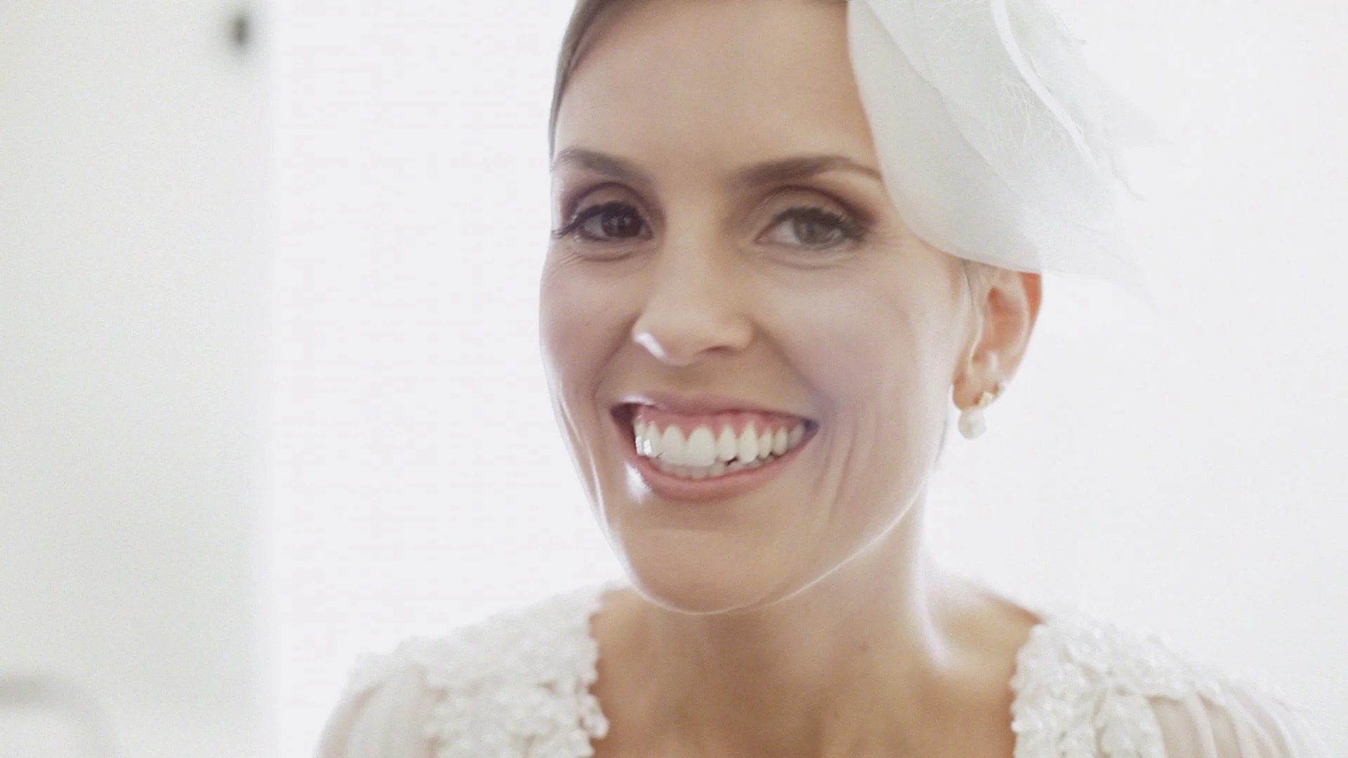 Mulher sorrindo com vestido branco de casamento e véu
