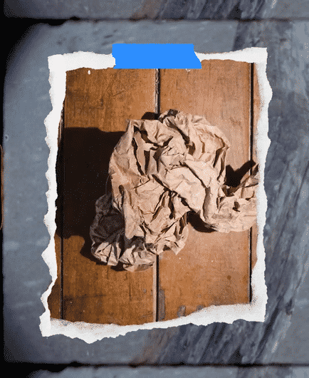 Crumpled brown paper on a wooden surface with a tear in the paper revealing a dark background.