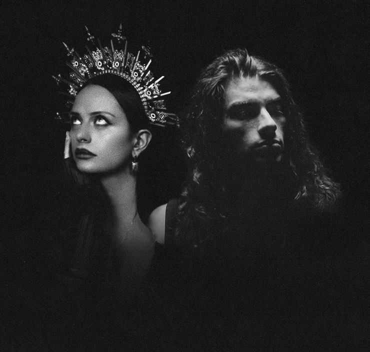 Black and white photo of a woman wearing a headpiece with spikes and circles, looking upward, and a Persian man with long, curly hair, looking forward, both with serious expressions.