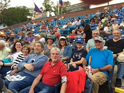People sitting in stadium bleachers at an outdoor event.