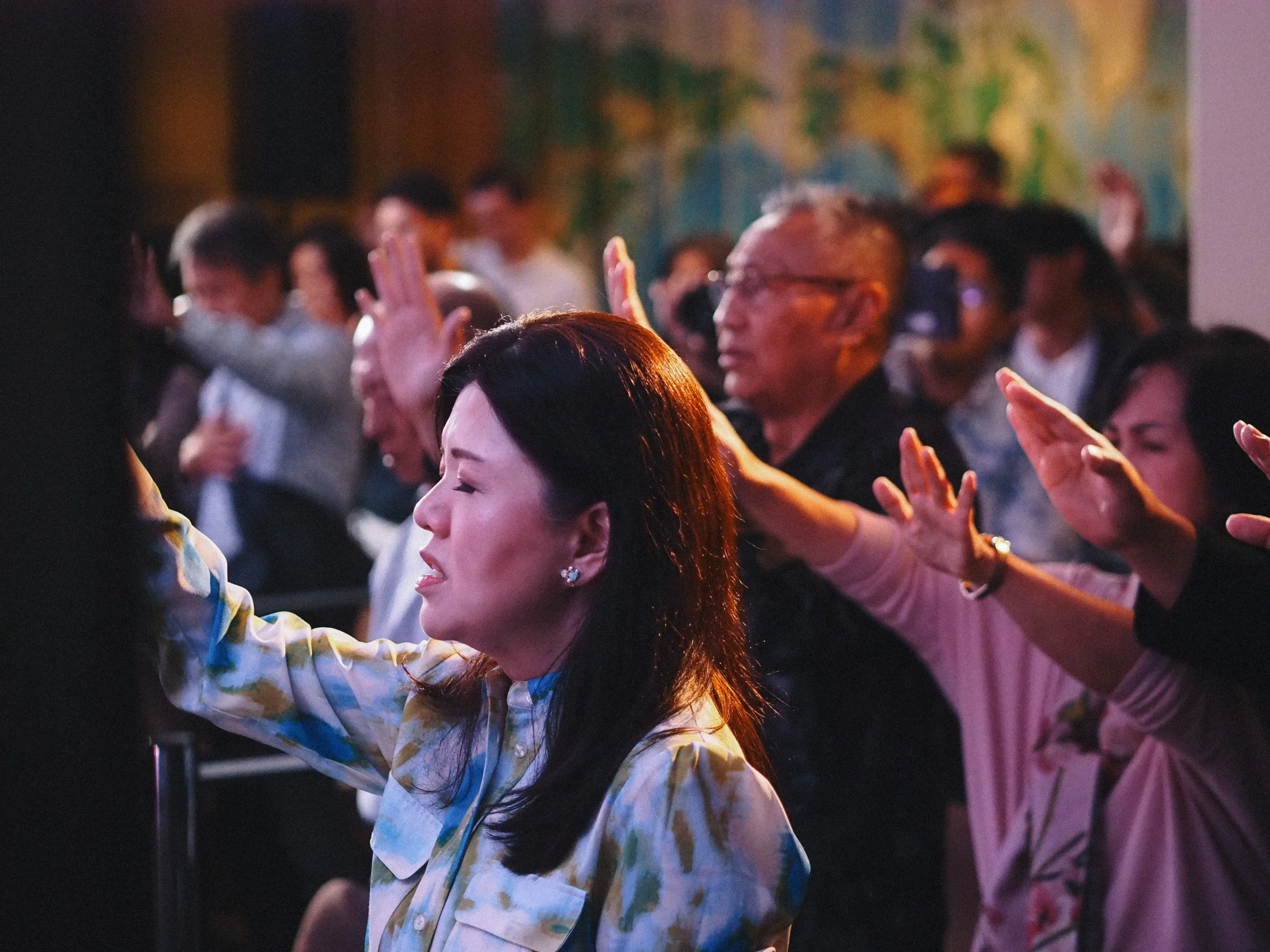 People in Sunday Service raising their hands in prayer and worship.