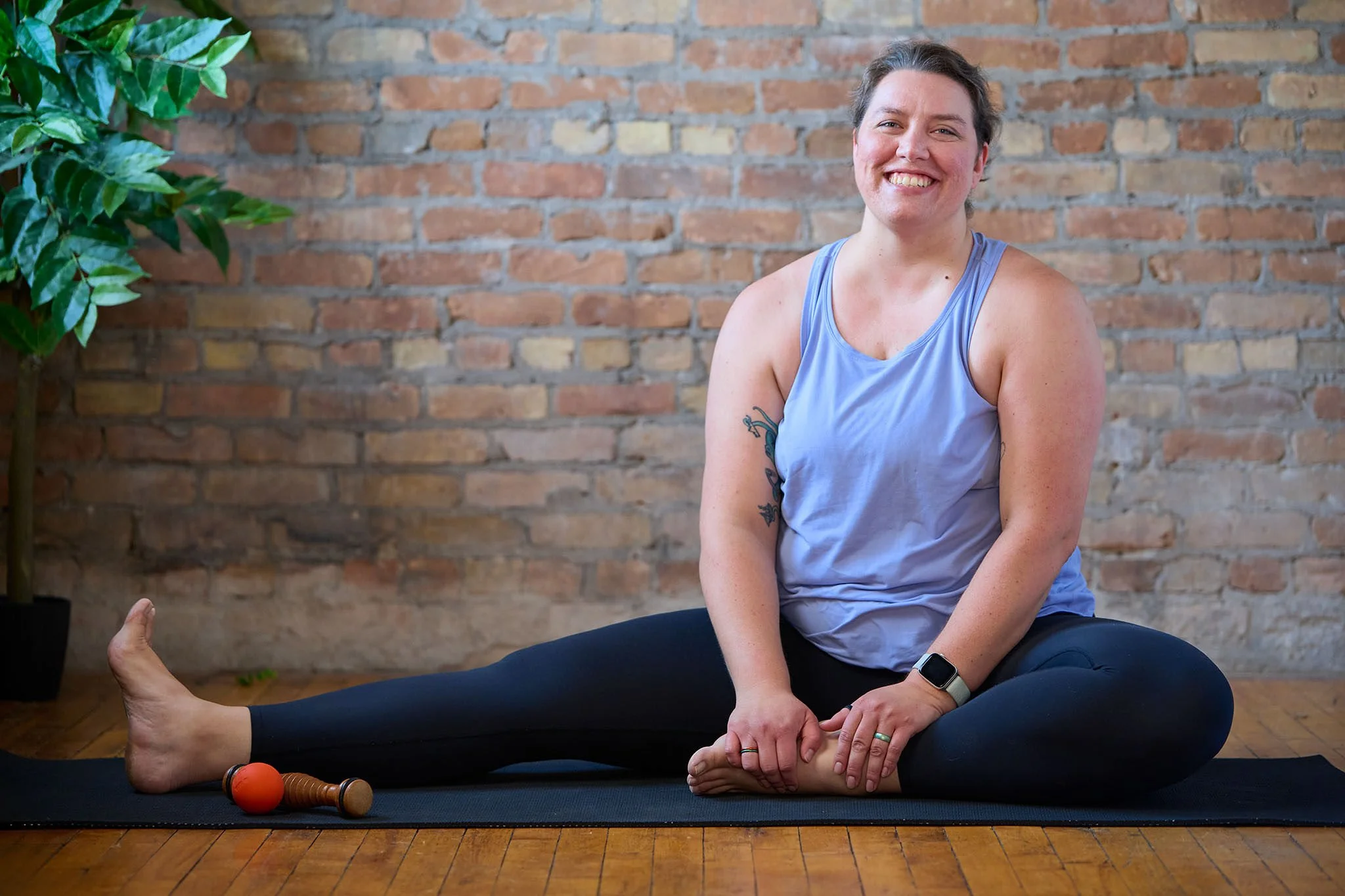 Marta sits on a yoga mat with one leg stretched out to the side.