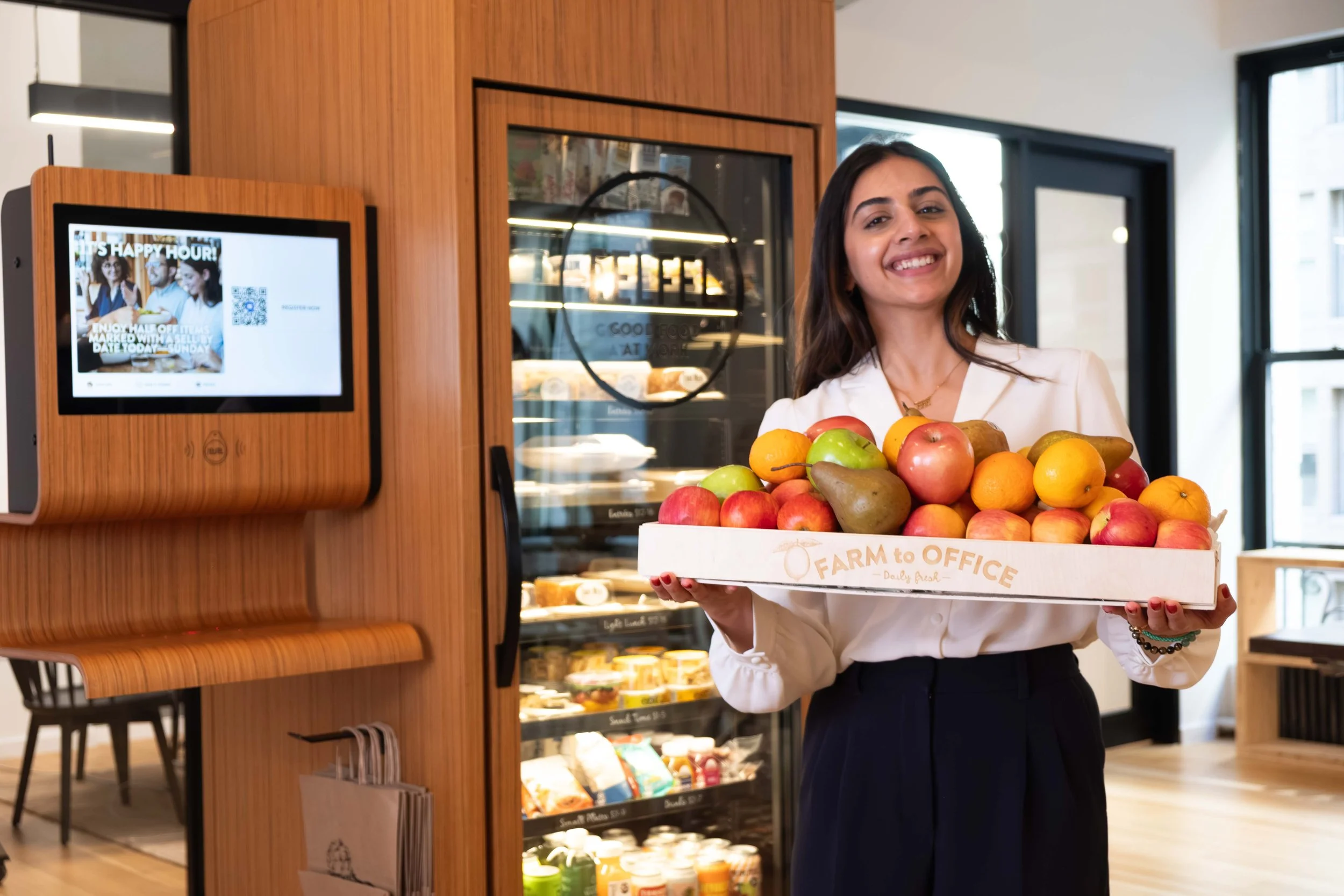 A hospitality manager holding a wooden tray of farm fresh fruits in the office