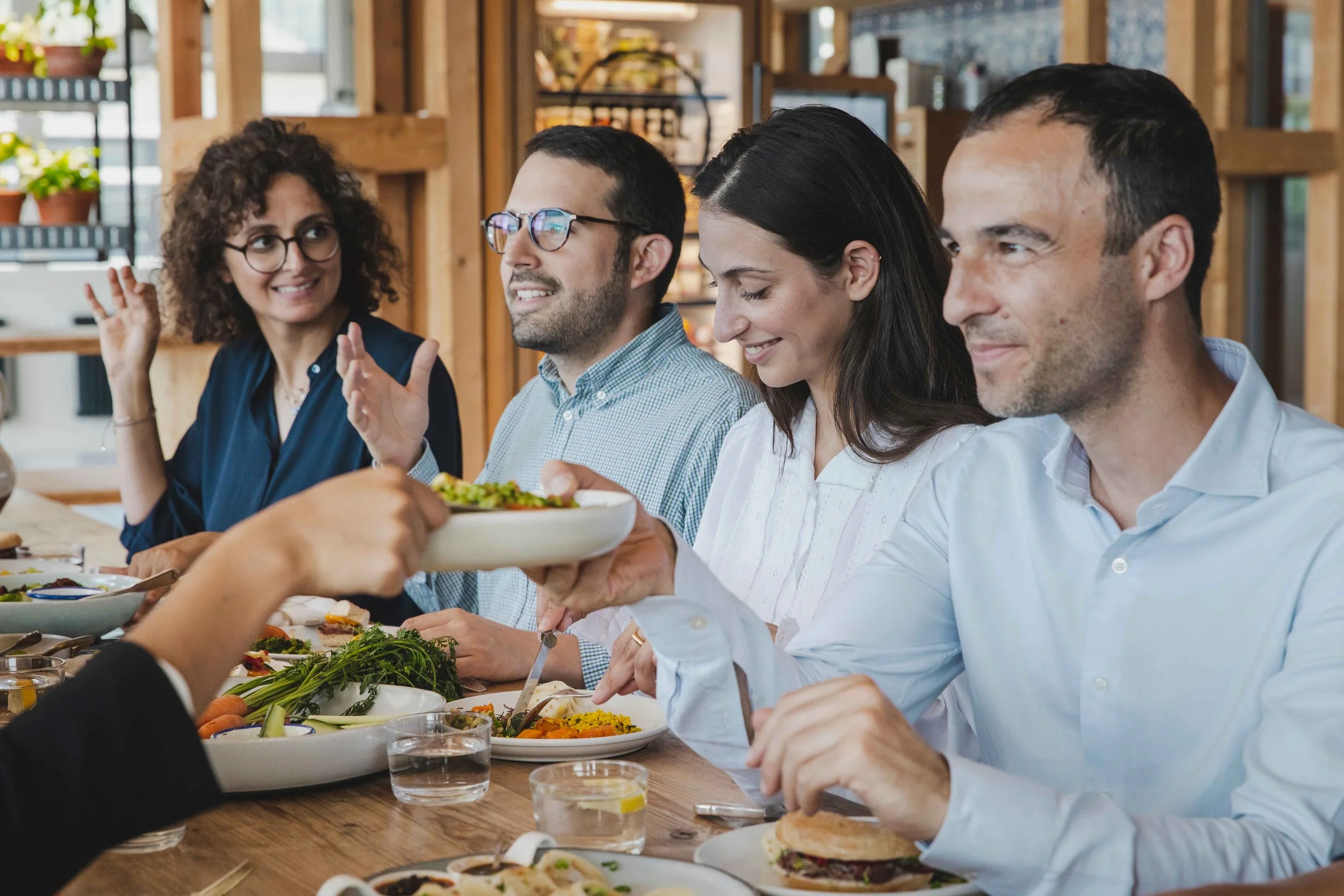 Group of four adults sitting at a dinner table, being served food in a cozy, rustic restaurant.