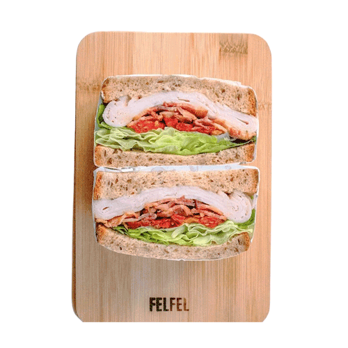 Gourmet Vending machine with Two halves of a sandwich with lettuce, tomato, turkey, and mayonnaise on whole grain bread, on a wooden cutting board.