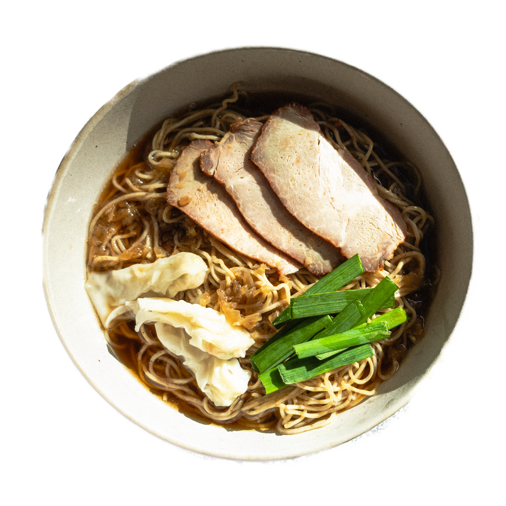 A bowl of ramen noodles topped with slices of pork, chopped green onions, and dumplings in broth.