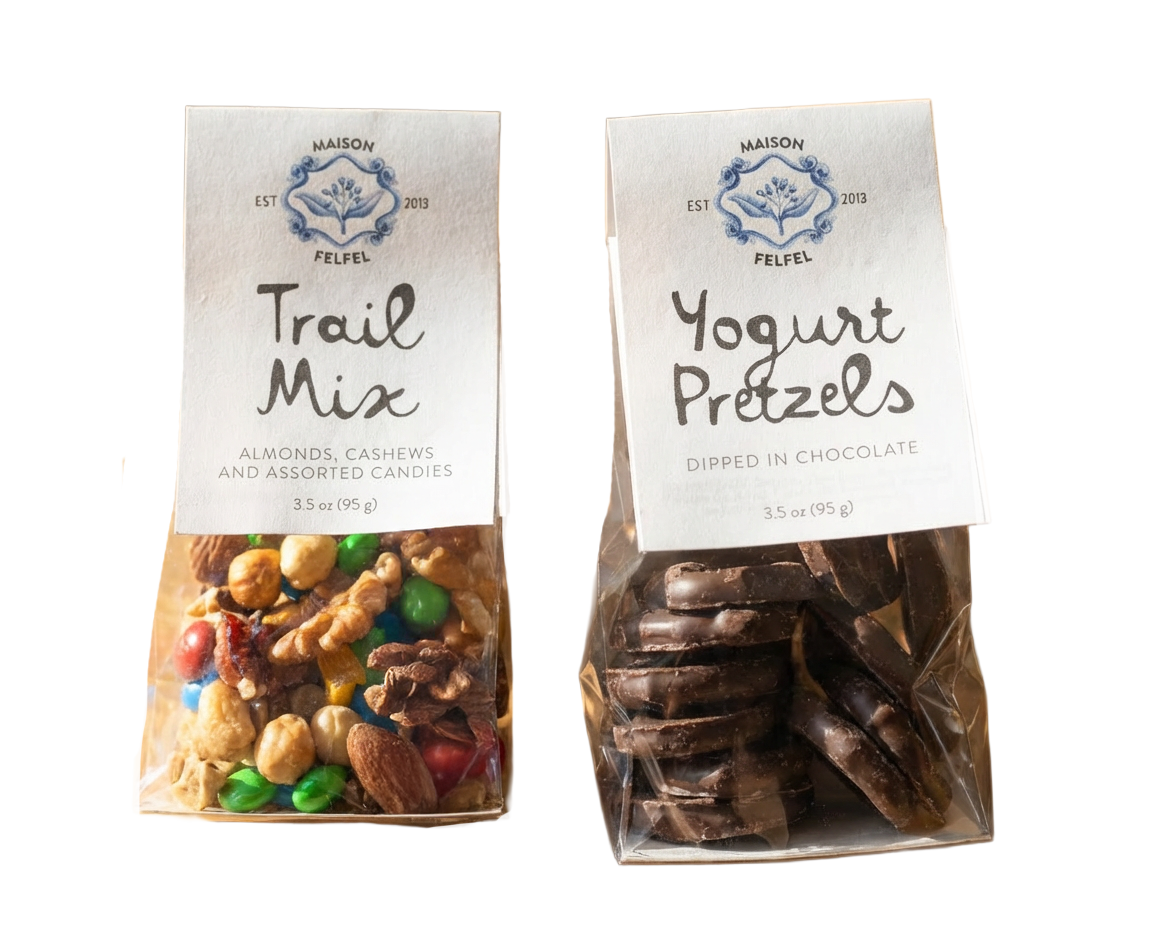 Two clear plastic bags, one with trail mix including almonds, cashews, candies, and peanuts, and the other with yogurt pretzels dipped in chocolate, labeled from Maison Felfel.
