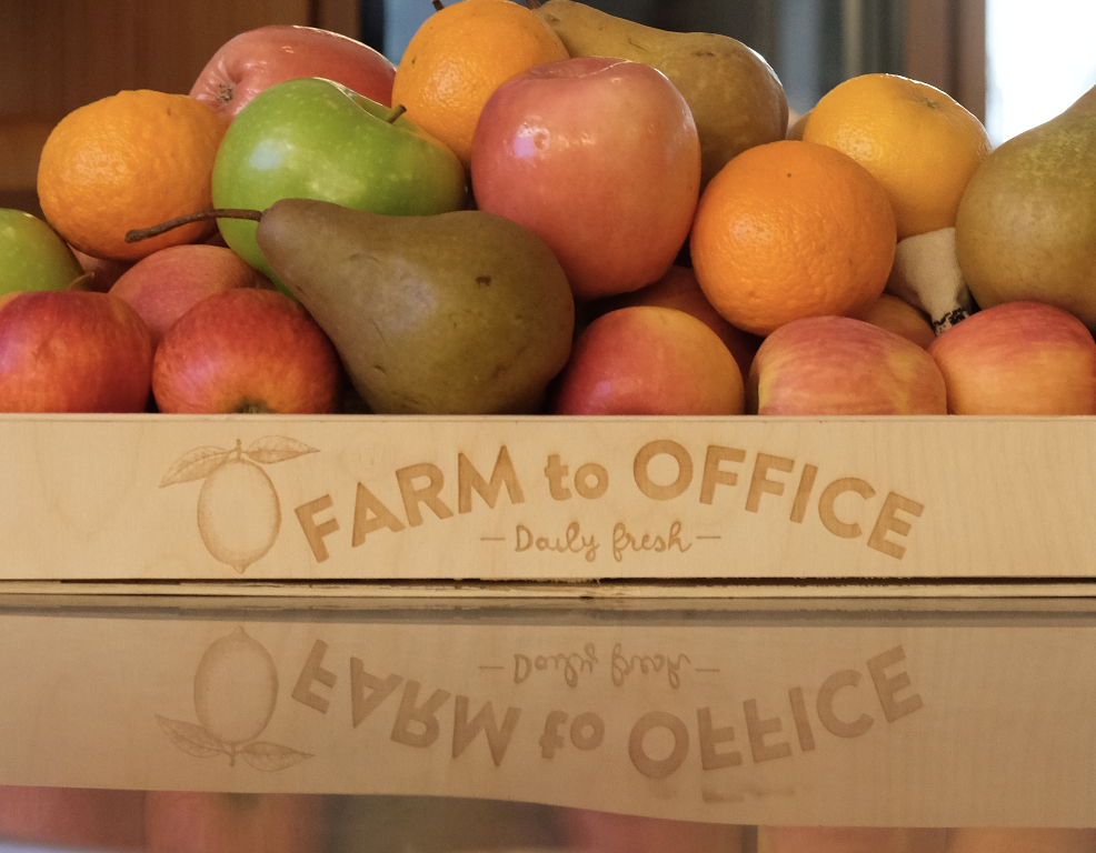 A wooden box filled with apples, oranges, pears, a banana, and a peach. The box has