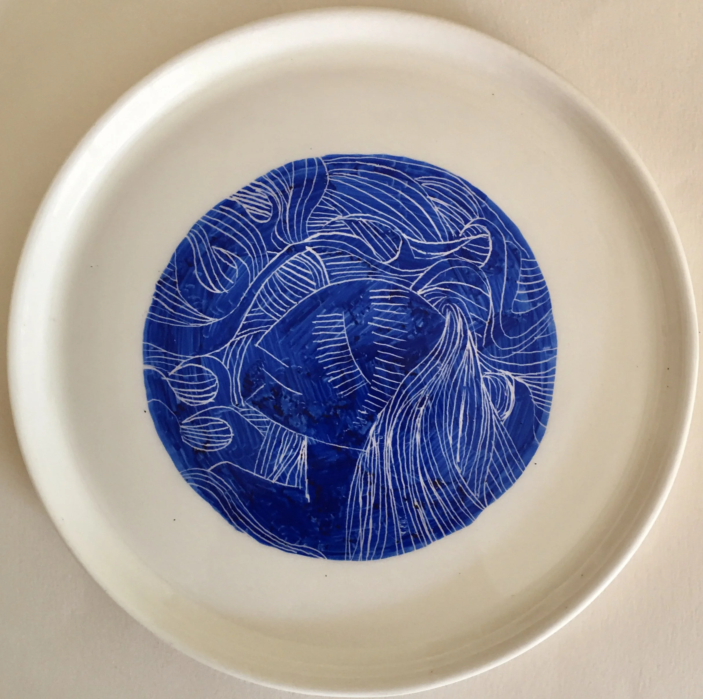 White plate with an intricate design of white lines on a blue background.