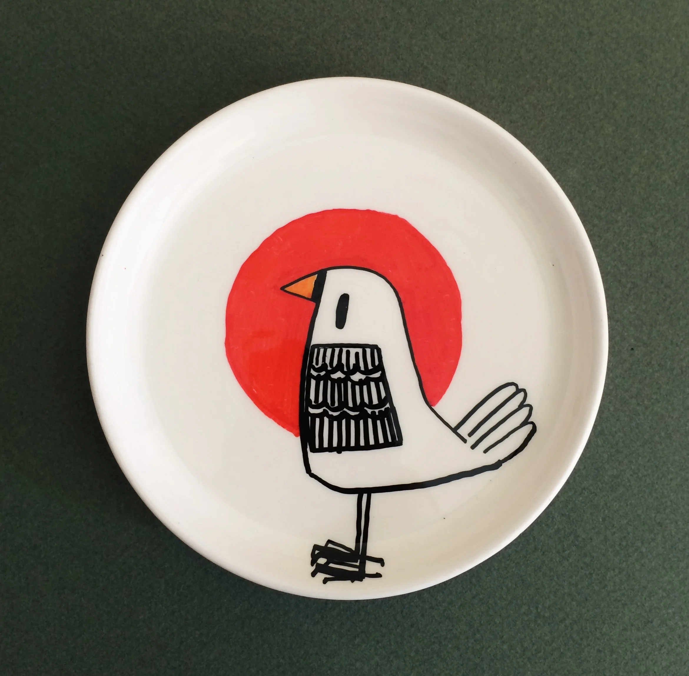 Decorative plate featuring a drawn bird with a red circle background.
