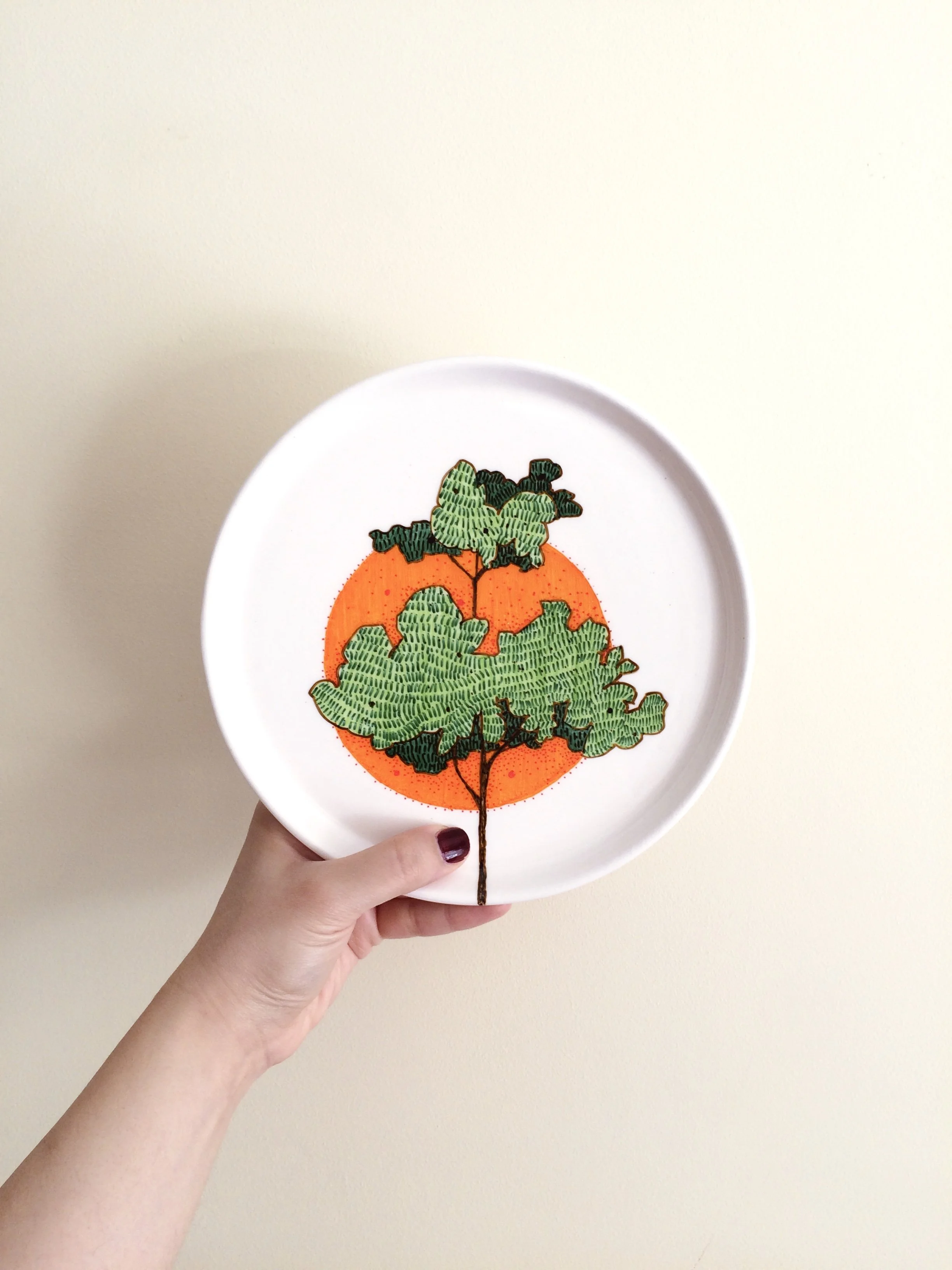 A decorative plate with an illustration of a pumpkin and green tree leaves against an orange circle background.