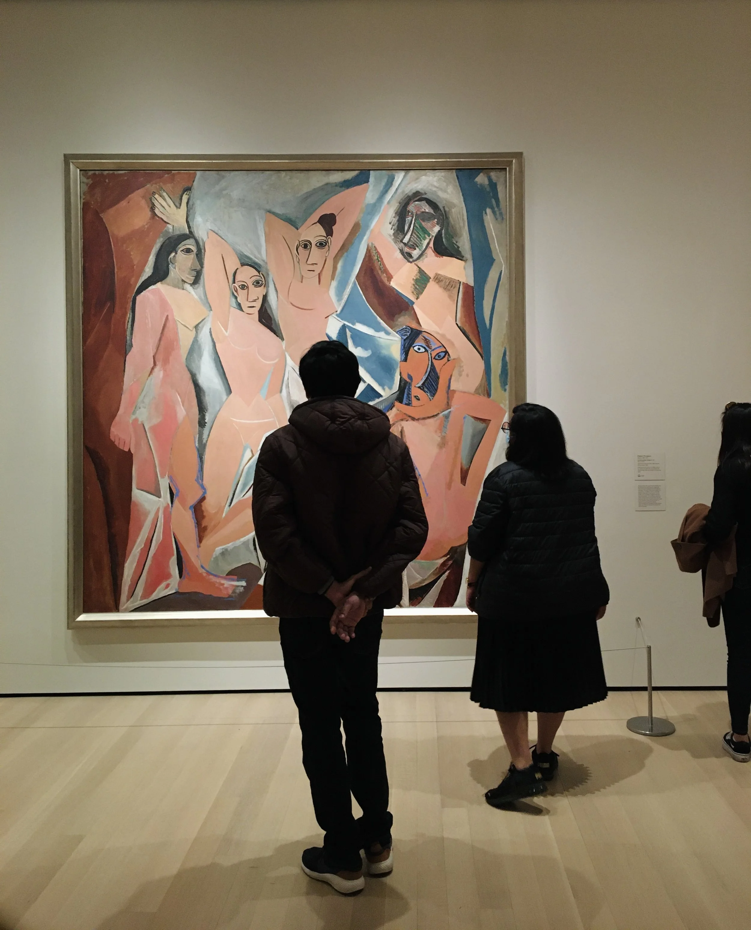 People viewing a large abstract painting with figures in a museum gallery.