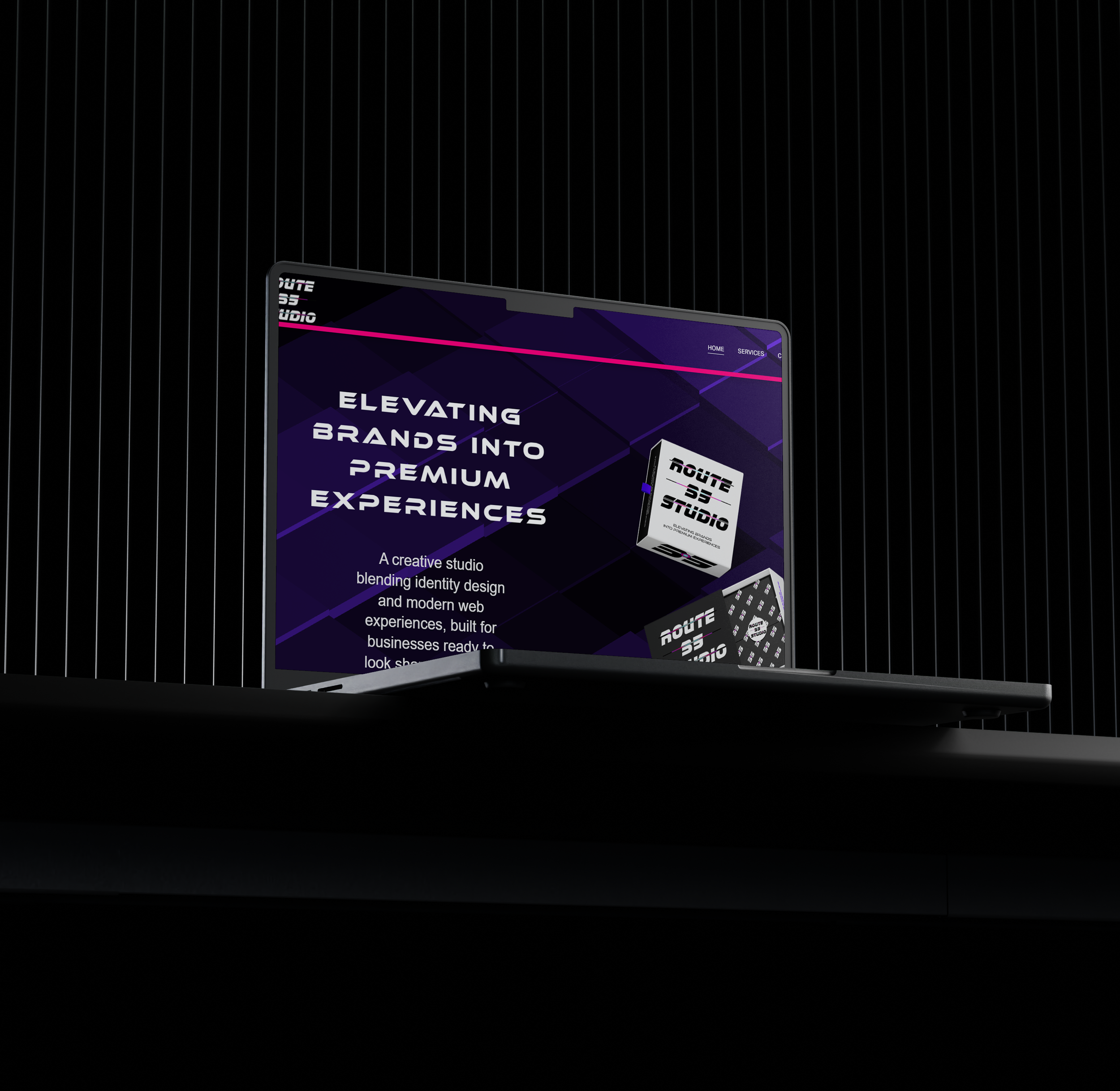 Laptop on a black surface displaying a website for a creative studio with a dark purple background, text about elevating brands, and images of branding products.