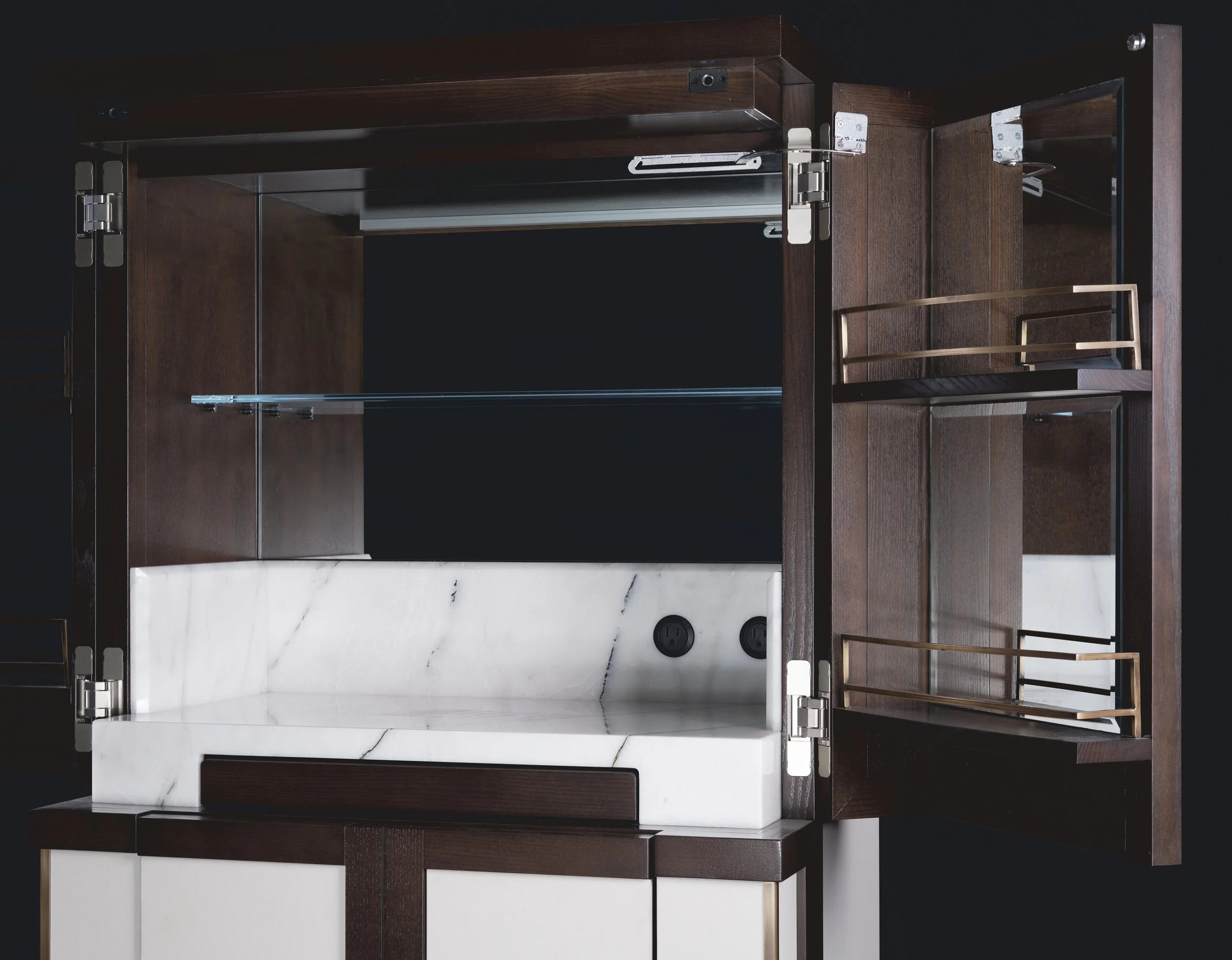 Une vitrine en bois sombre avec des étagères en verre, un comptoir en marbre blanc et des prises électriques, avec des portes en verre latérales.