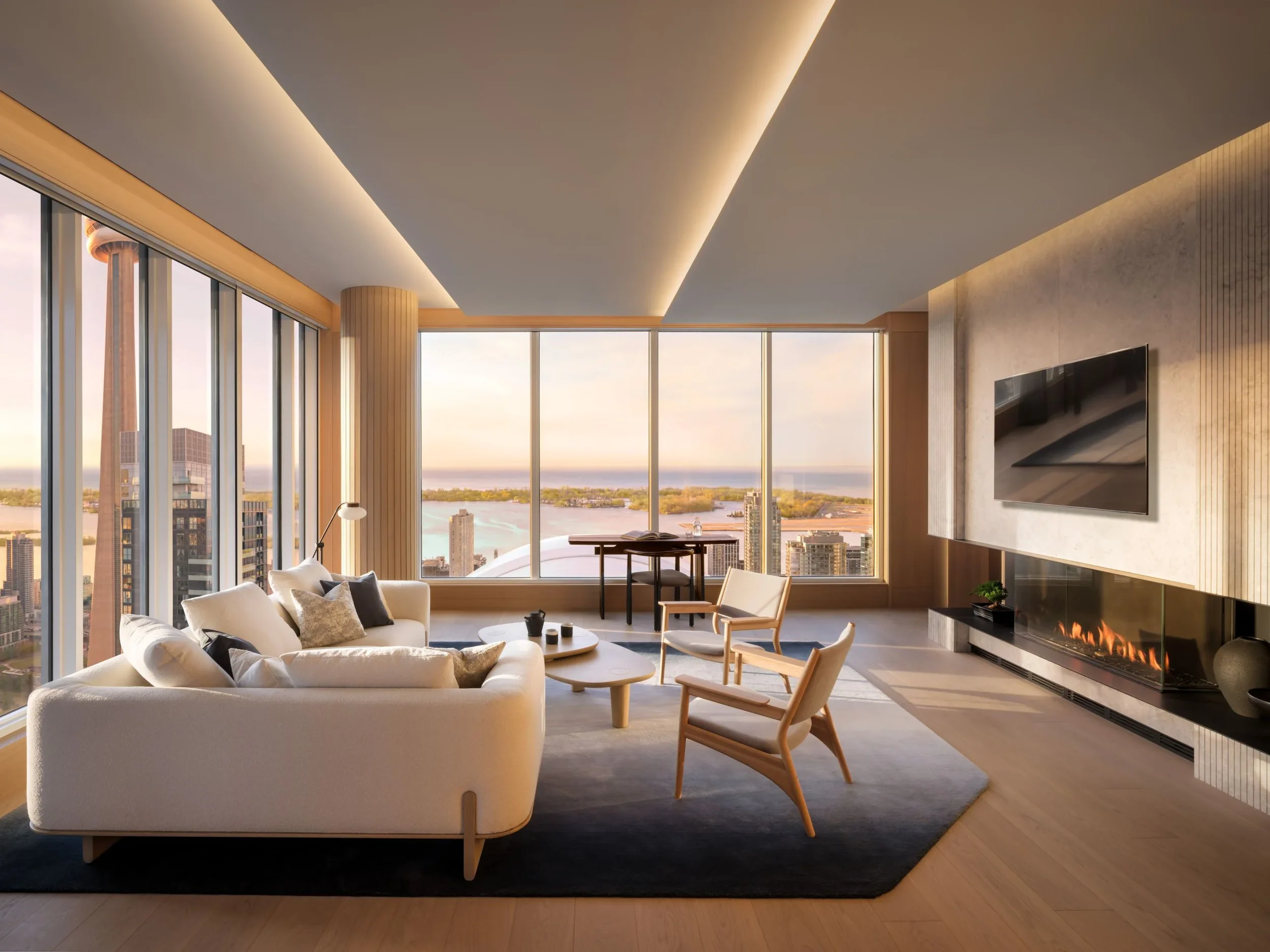 Salon moderne avec vue panoramique sur la ville et un fleuve, canapé blanc, fauteuils en bois clair, cheminée électrique, télévision murale, tapis gris, lampe sur pied, grande baie vitrée.