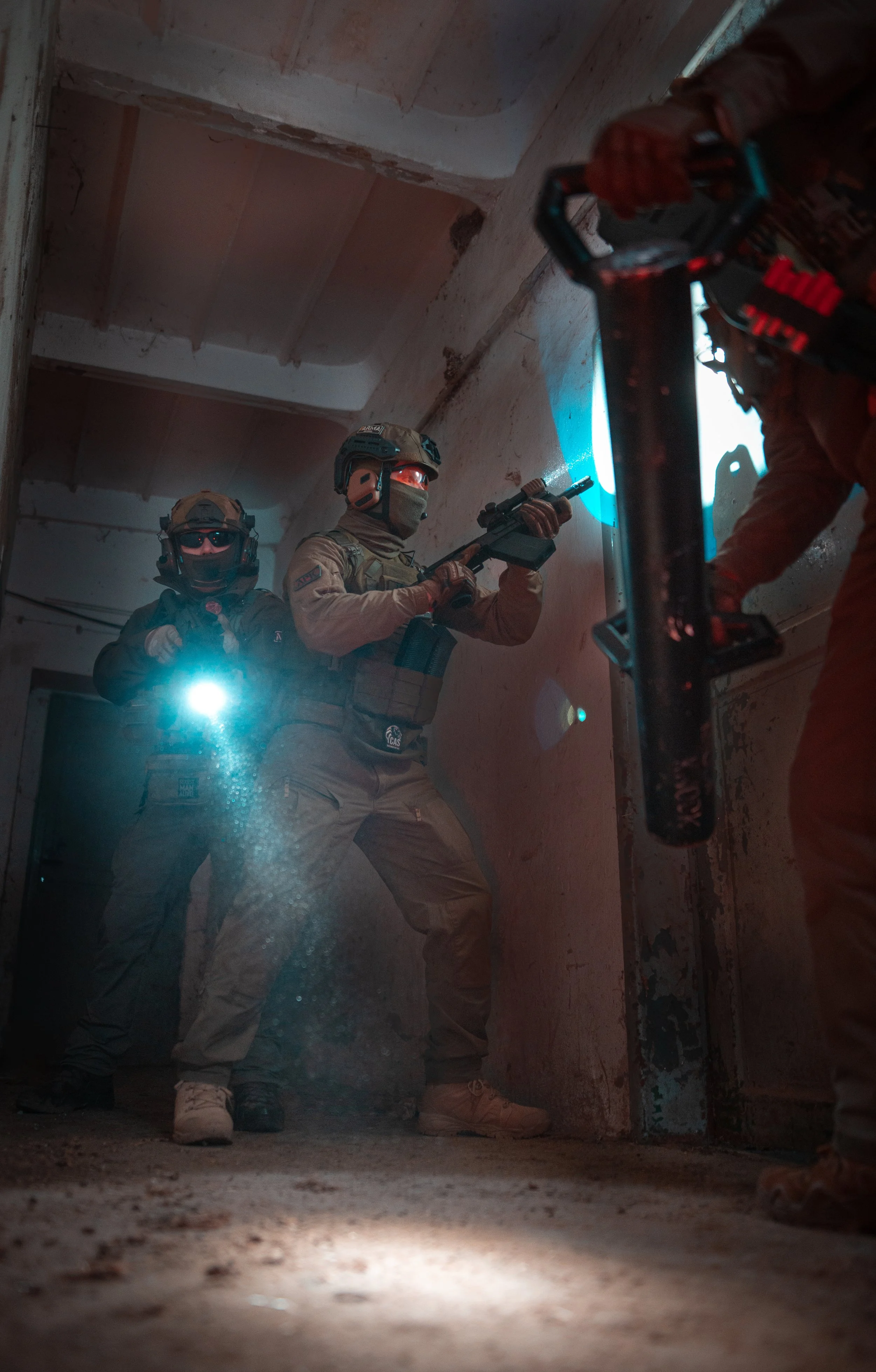 Two armed tactical officers in military gear practice breaching a door with a flashbang during a training exercise.