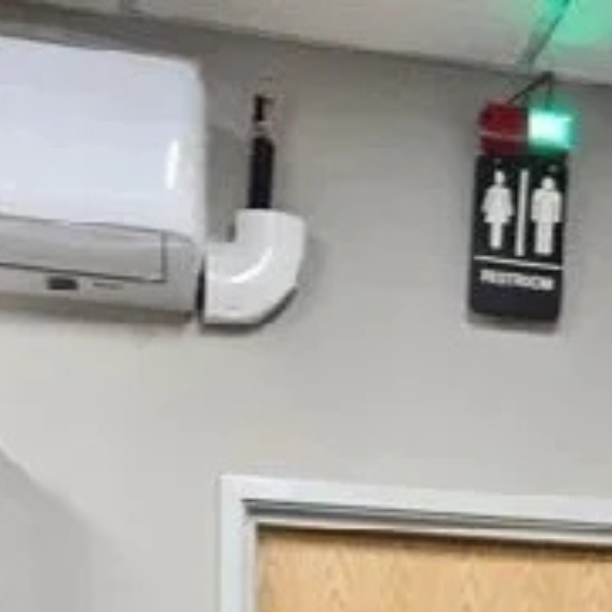 Comparison of two restroom doors with electronic signs; the left door has a red light indicating occupied, and the right door has a green light indicating available. The signs feature male and female icons. The photo was taken at the Polk County Sher