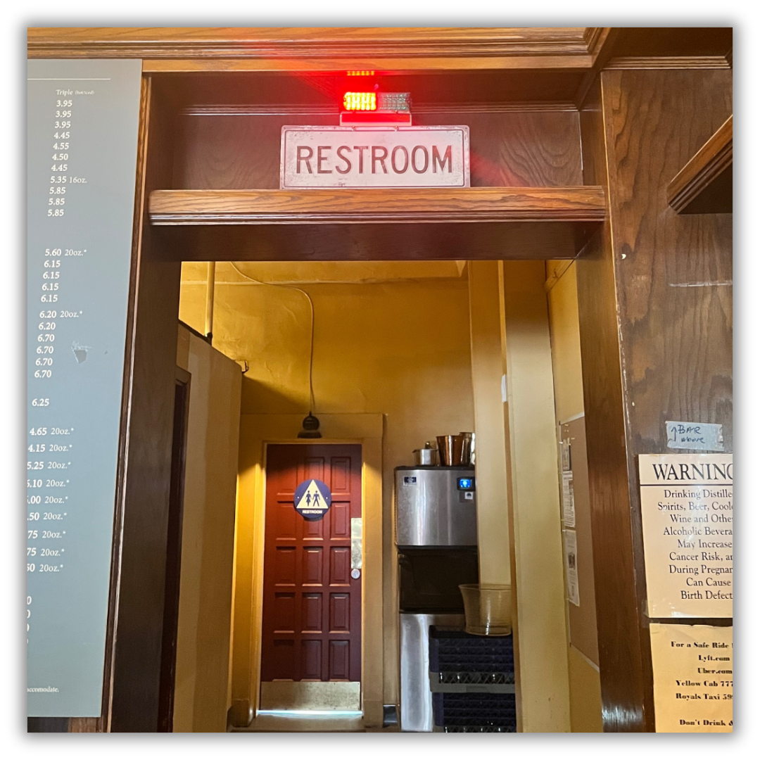 Commercial bathroom occupied light mounted above the door frame at a distance from the restroom door