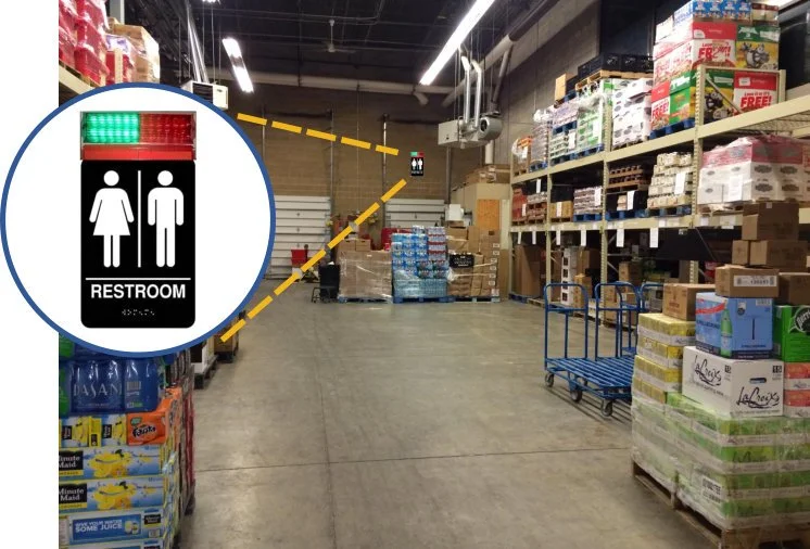 Store aisle with shelves stocked with boxes and packages, and a restroom sign indicating men's and women's restrooms.