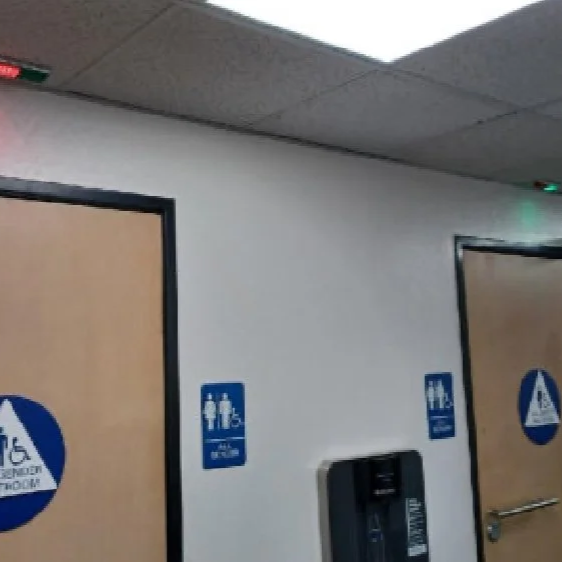 Restroom doors with accessibility signs and a wall-mounted hand sanitizer dispenser.