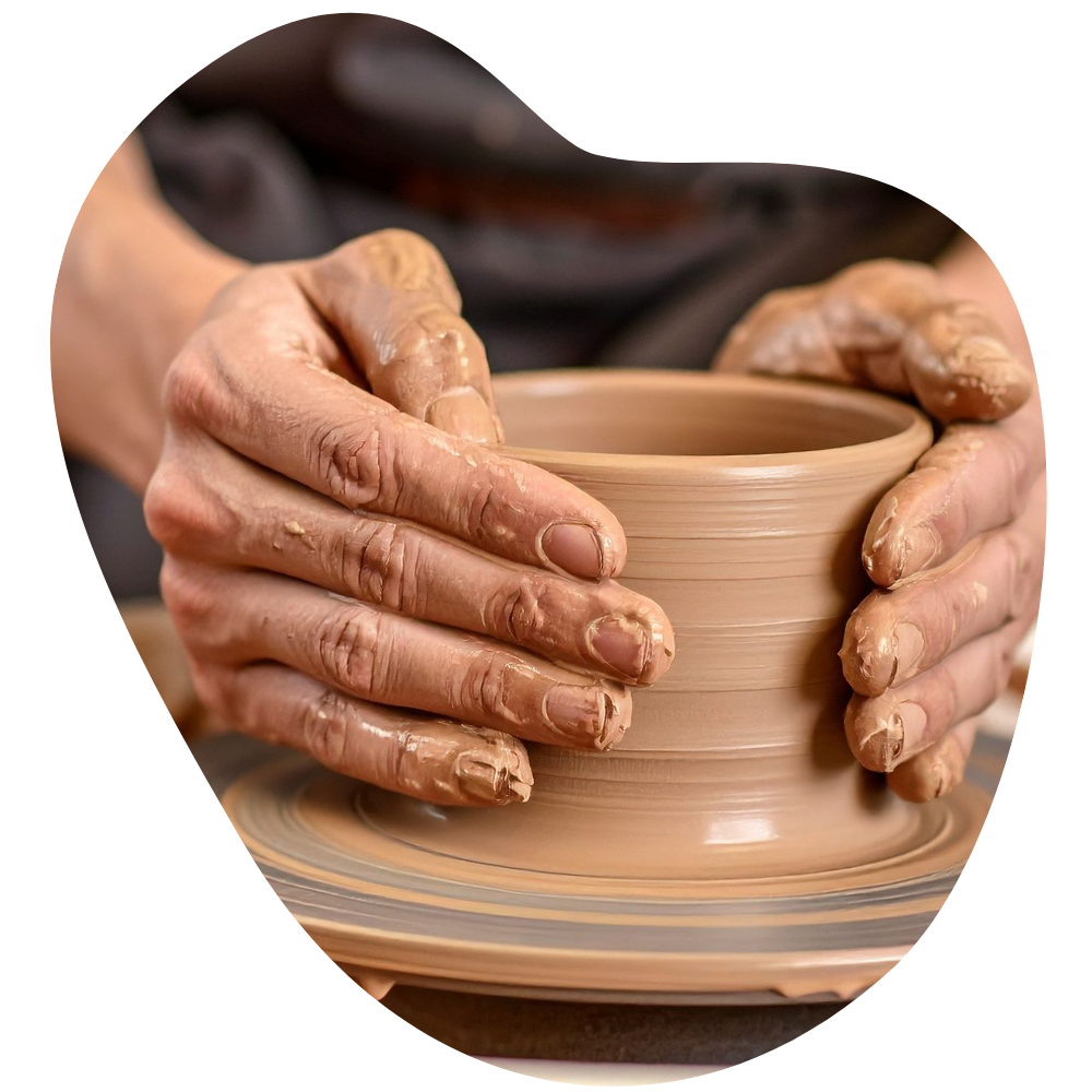 Hands shaping a clay vessel on a pottery wheel.