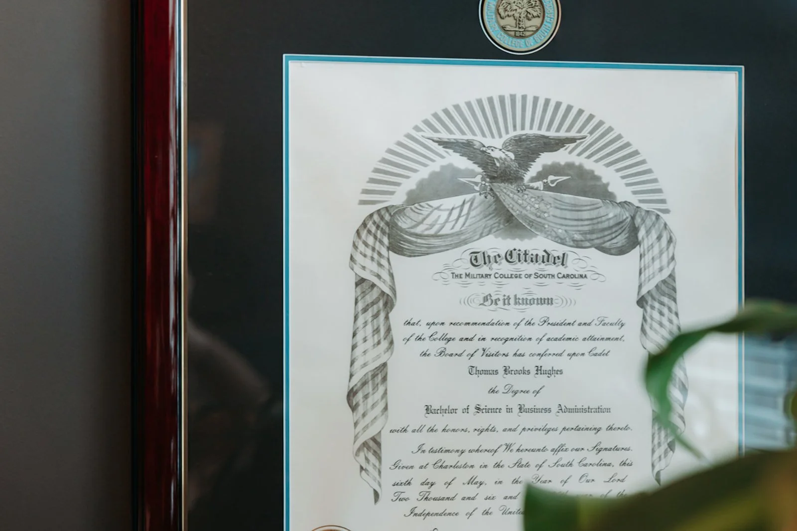 Framed diploma or certificate from The Citadel, The Military College of South Carolina, with an eagle emblem at the top, featuring an eagle with outstretched wings holding a banner, surrounded by a decorative cloth.
