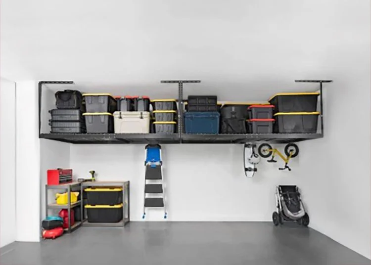 Garage wall with storage shelf holding plastic bins, a small blue chair on a ladder, wall-mounted bicycle, and a stroller on the floor.