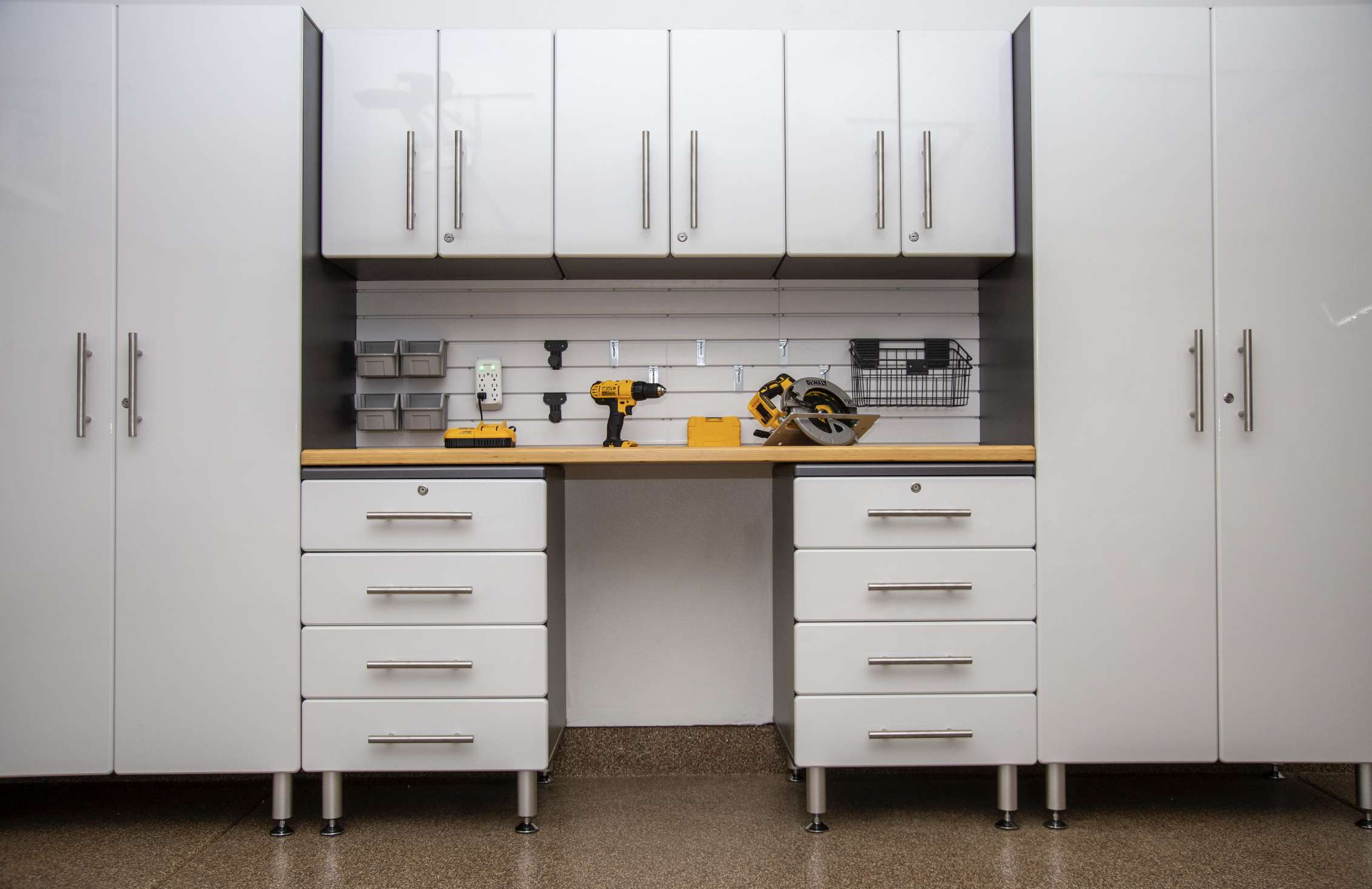 White garage workshop with tools and storage cabinets, power drill, circular saw, and organized wall hooks.