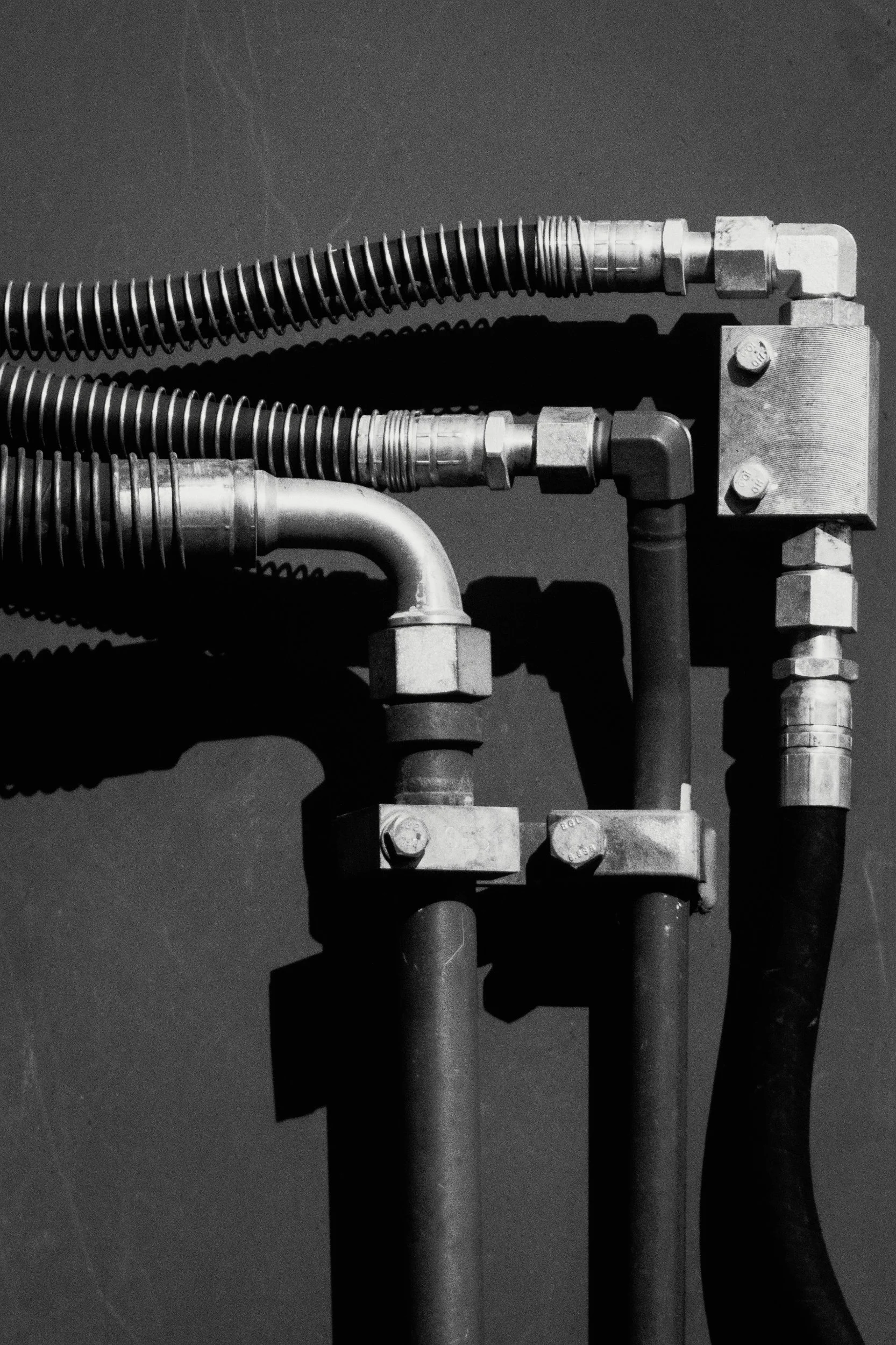Clean geometry in high-contrast light—hard metal lines and hydraulic hoses on heavy machinery