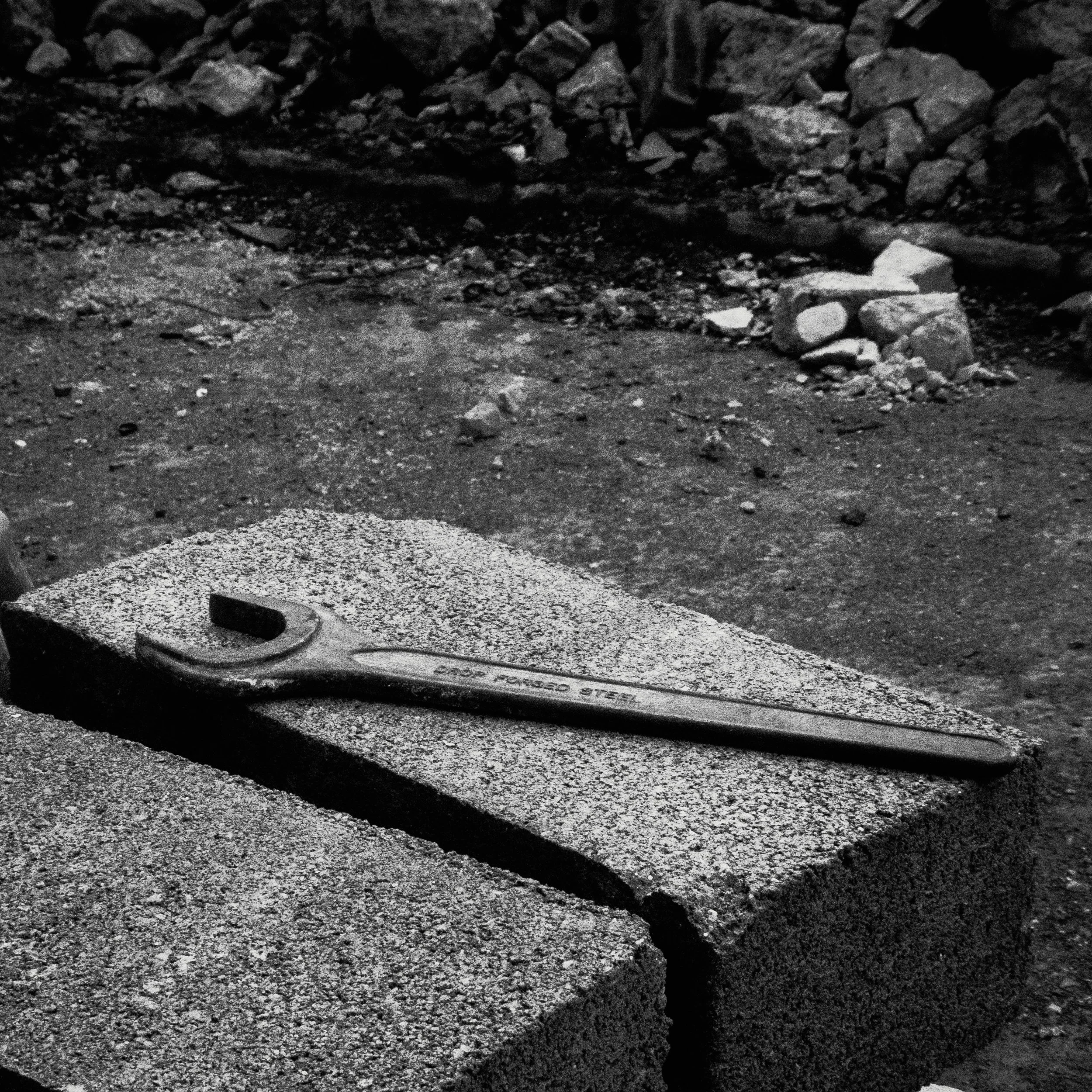 A drop-forged spanner left resting on split blockwork. A small trace of the manual labour driving the shift forward.