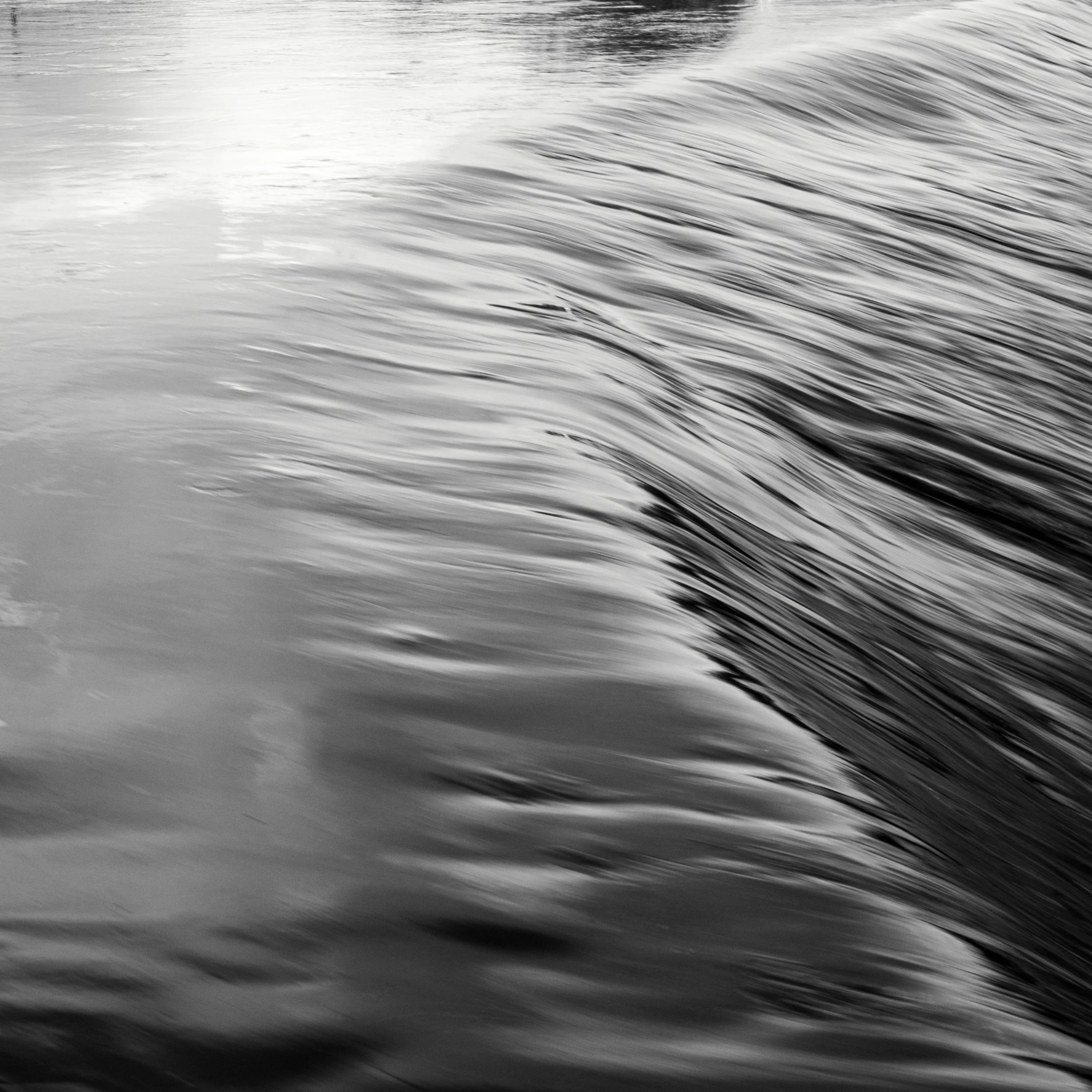 Black and white long exposure of smooth flowing river water creates abstract water photography.