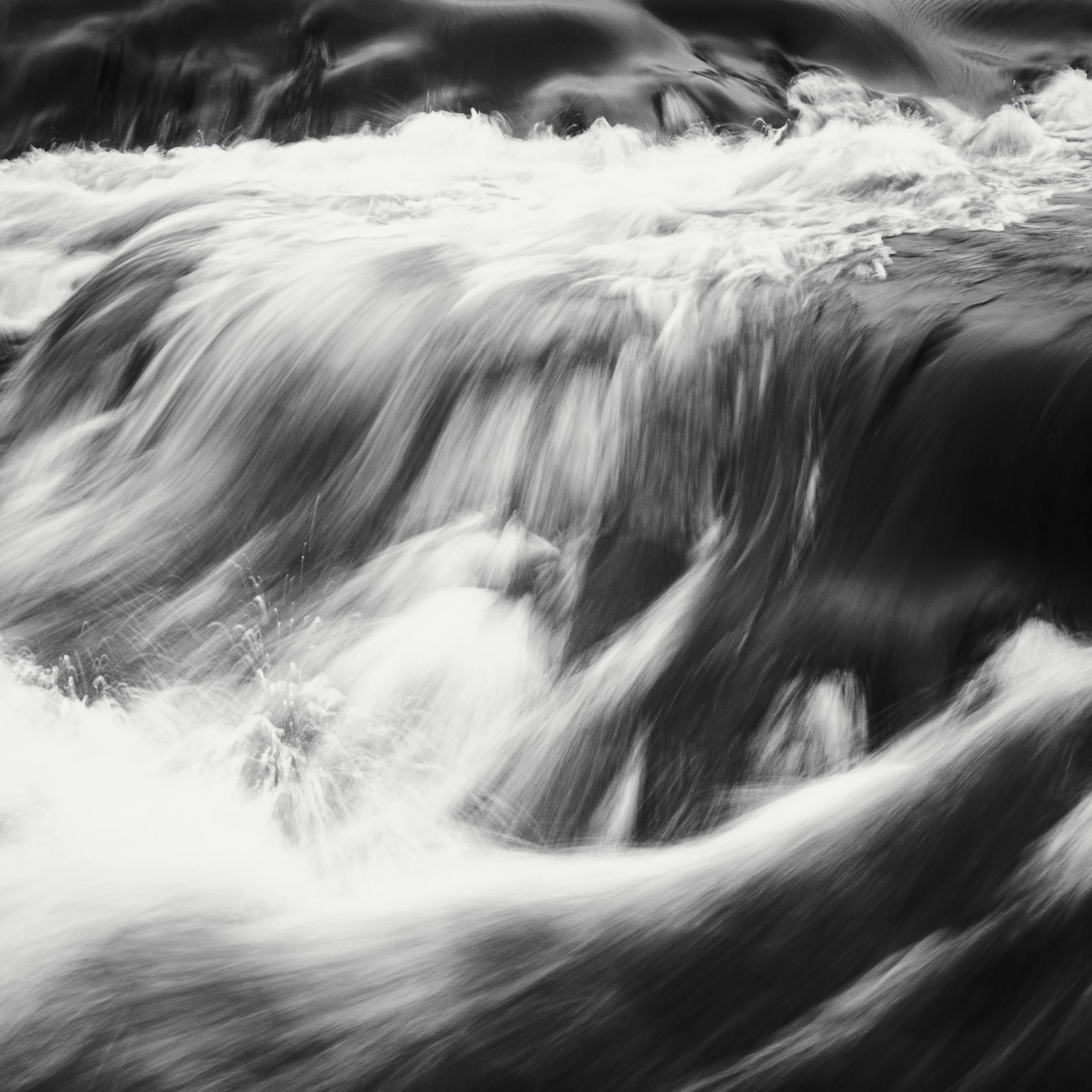 Dramatic black and white photograph using slow shutter speed to capture the smooth flow of a waterfall.