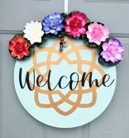 Handmade Decorative welcome sign with colorful paper flowers on the top and a printed geometric design with the word "Welcome" in the center.