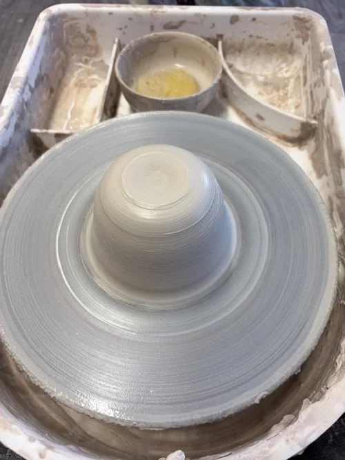 Make your own pottery. A potter shapes a ceramic bowl on a spinning pottery wheel with wet clay, surrounded by clay splatters and tools.