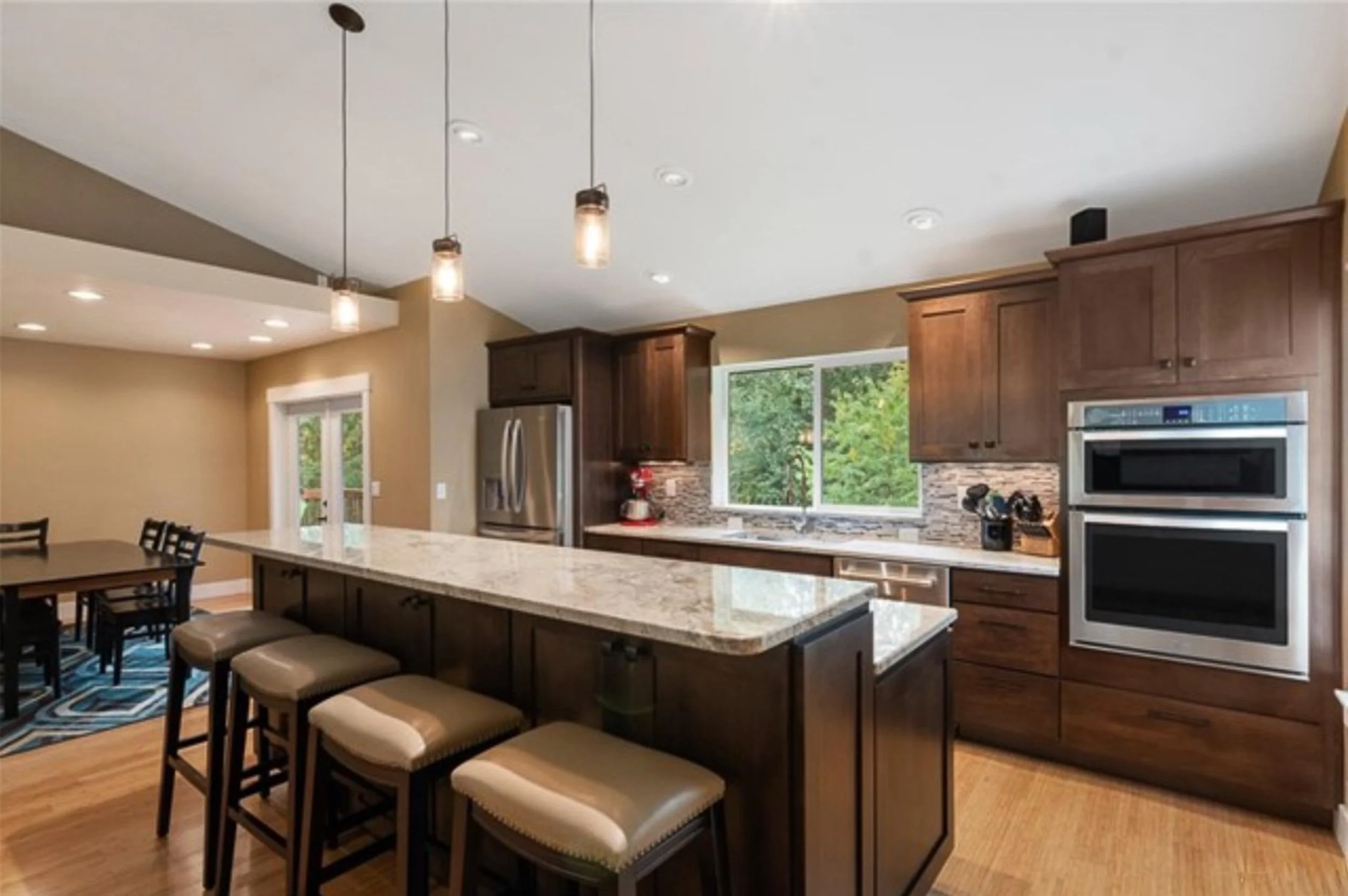 Open-concept kitchen and dining area with vaulted ceilings and elegant pendant lighting. This Kitsap home transformation emphasizes a bright, spacious layout and seamless natural flow.