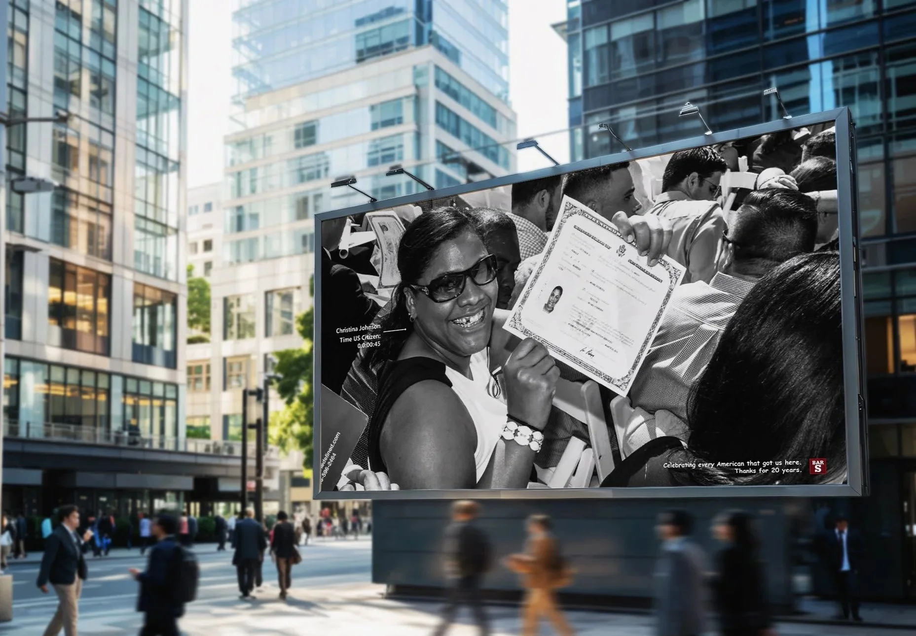Black and white billboard showing a woman smiling, holding a certificate. The background shows a crowd of people at an outdoor event with tall modern buildings around.