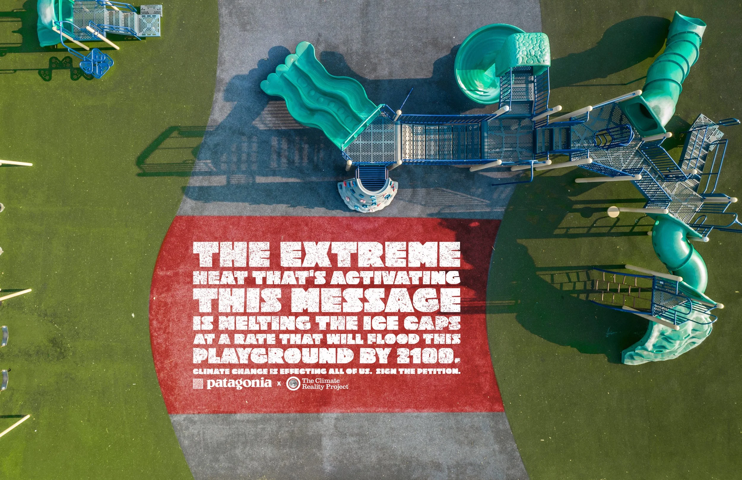 An aerial view of a playground with a large red and gray message on the ground about the dangers of melting ice caps due to climate change, and various playground equipment such as slides and climbing structures.