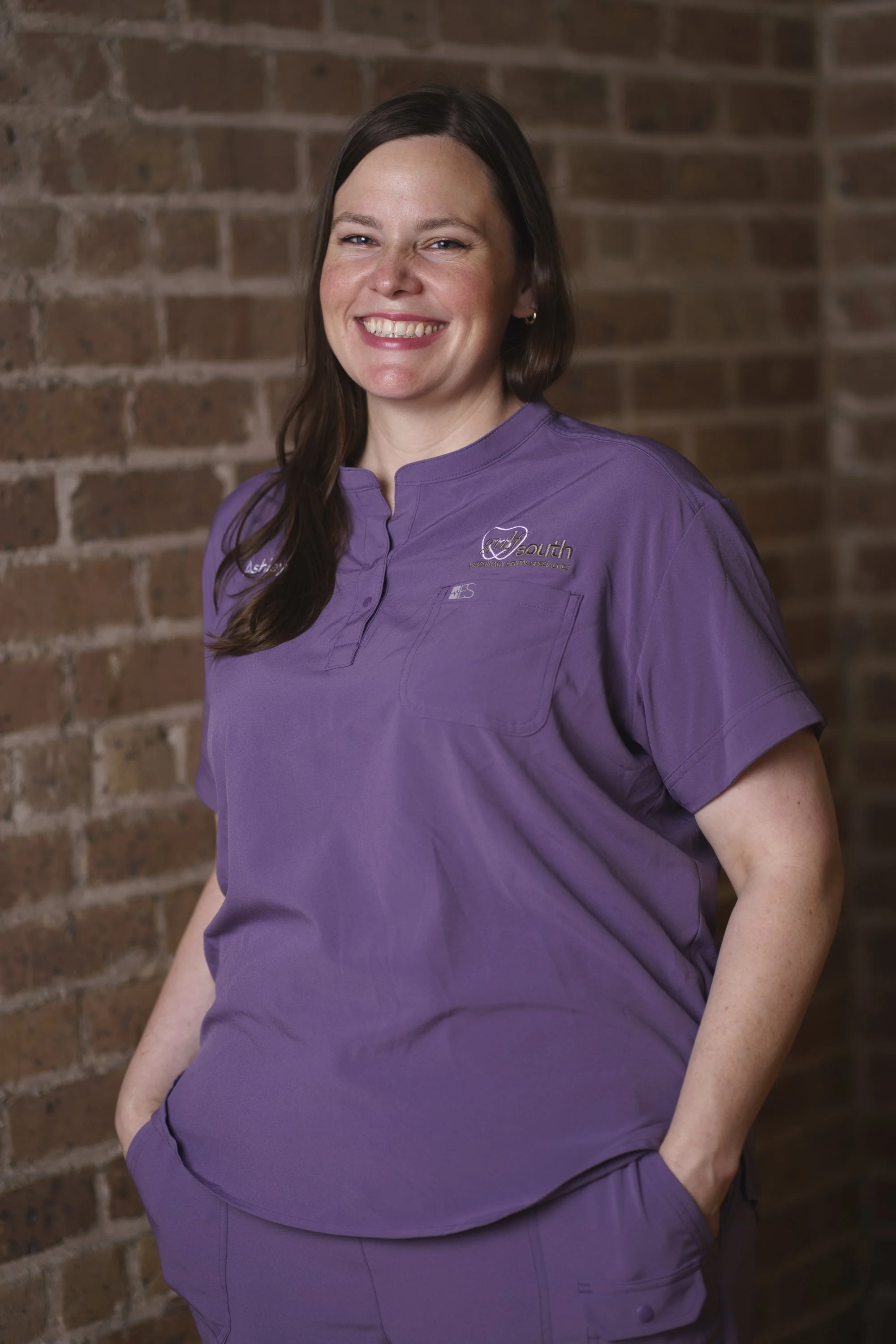Ashley Laguaite, Customer Service Representative at Gulf South Veterinary Dental Specialties. A woman wearing a veterinary dental specialties uniform, smiling with a brick wall background.