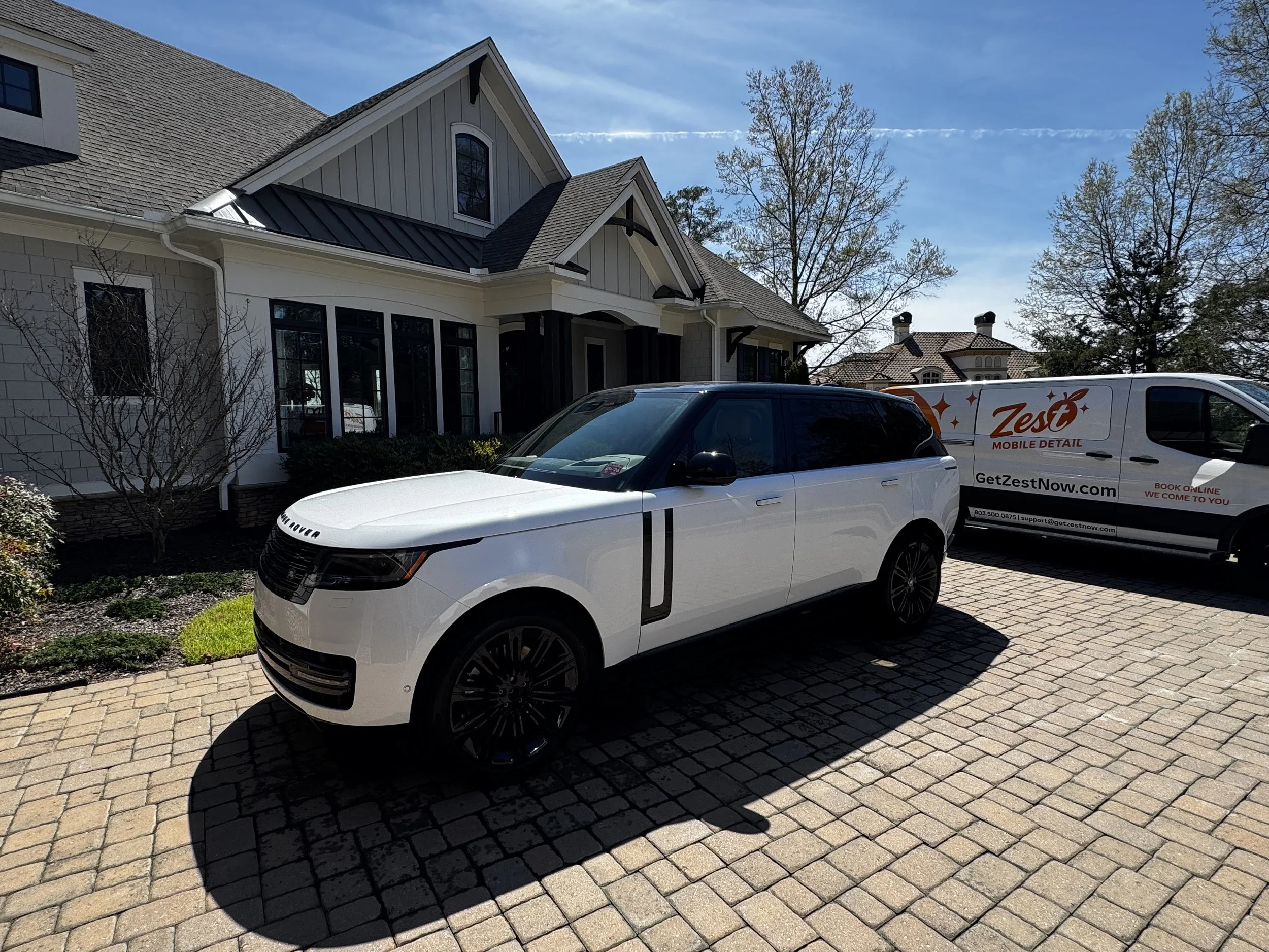 White Land Rover Range Rover freshly detailed by Zest Mobile Detail in Chapin, SC with a Zest mobile detailing van in the background, showcasing luxury mobile car detailing, exterior restoration, paint enhancement, and professional detailing.