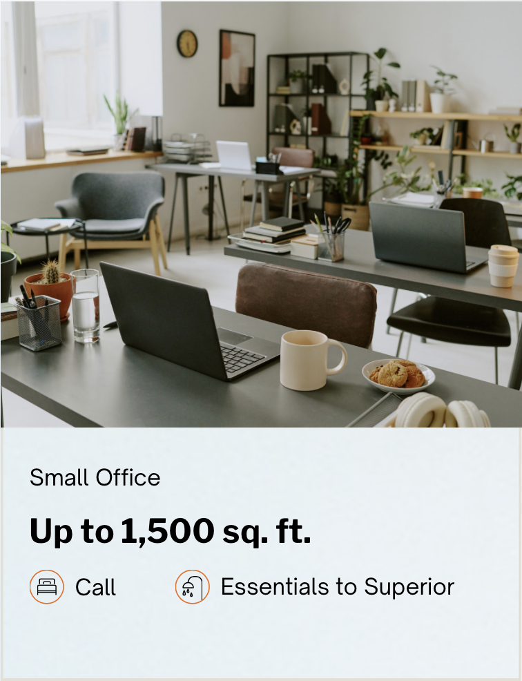 An office space with desks, laptops, chairs, and office supplies, decorated with plants and artwork.