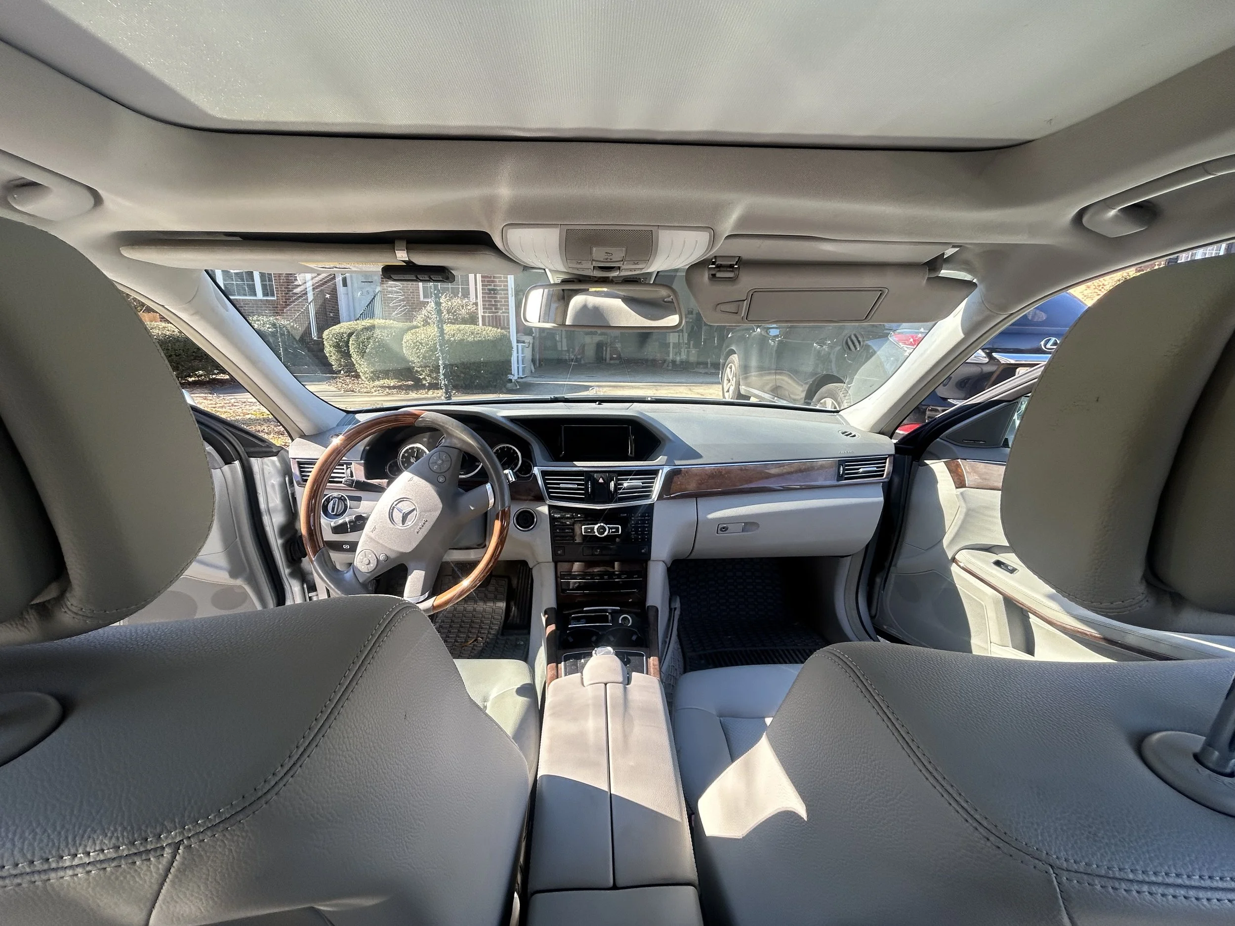 Interior view of a Mercedes-Benz vehicle with gray seats, wood accents, and a dashboard.