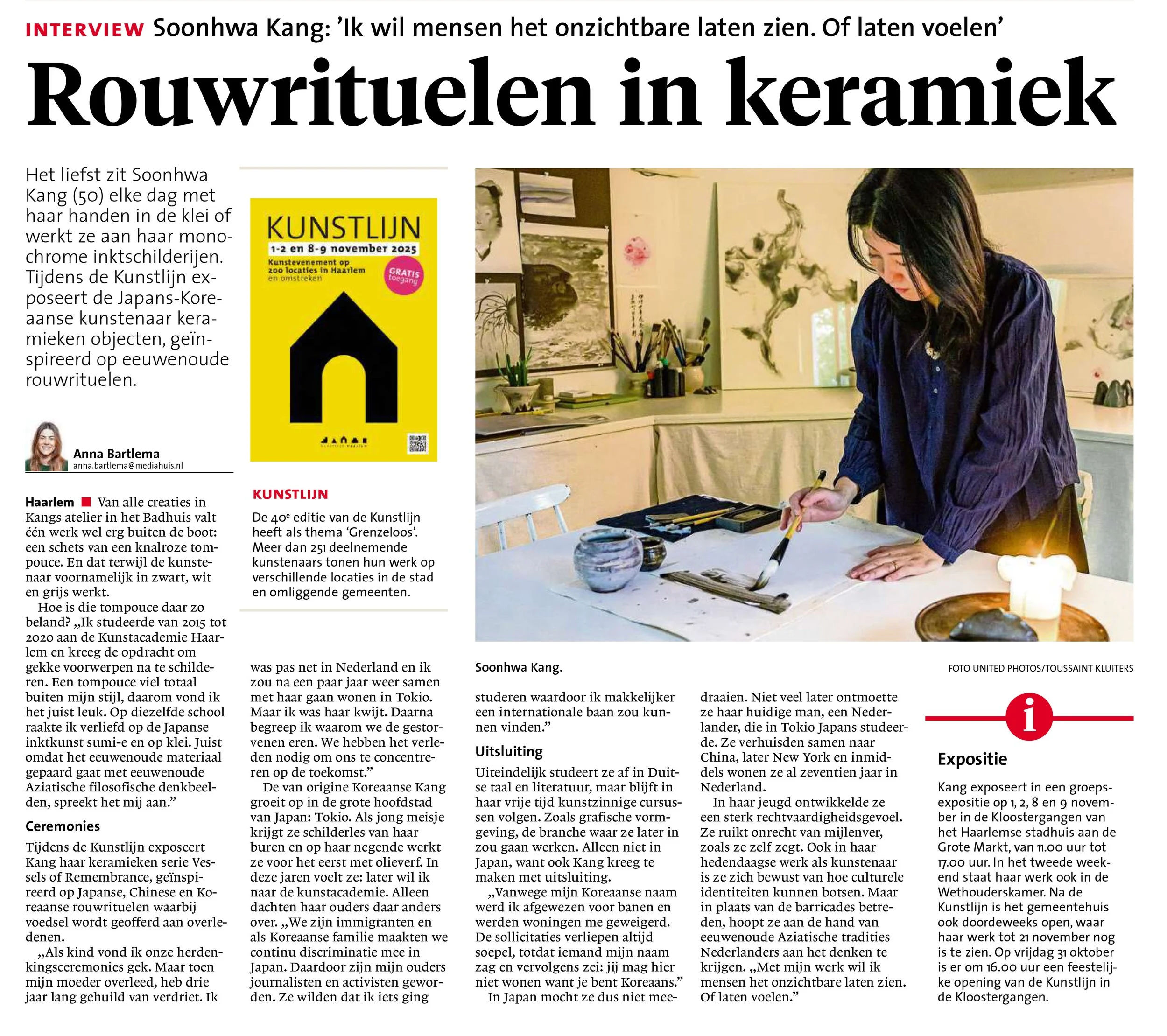 A woman painting with traditional Asian-style paintings in the background, sitting at a table with painting supplies, in an art studio or gallery setting.