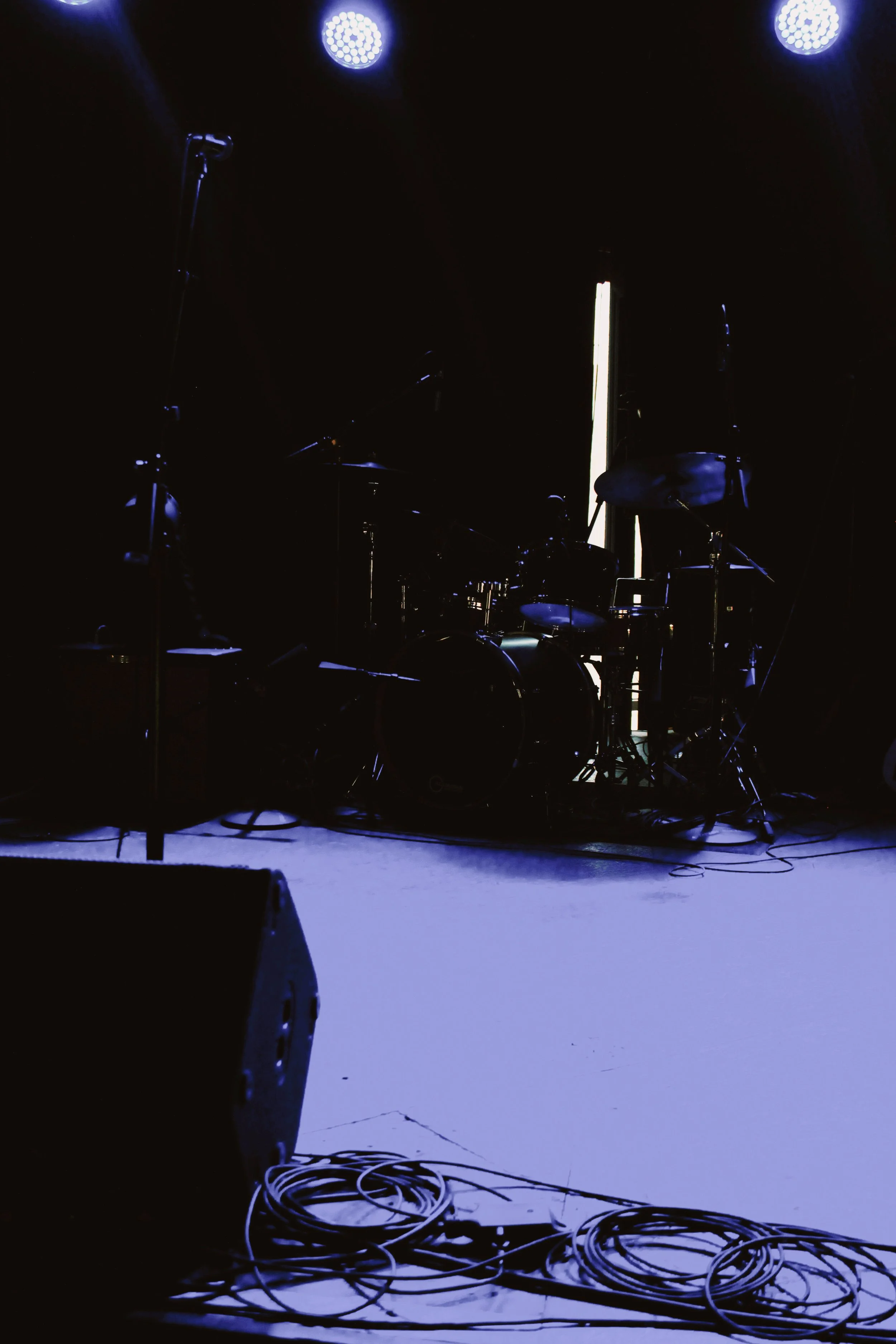 Empty stage with a drum set, microphones, and stage lights, ready for a performance.